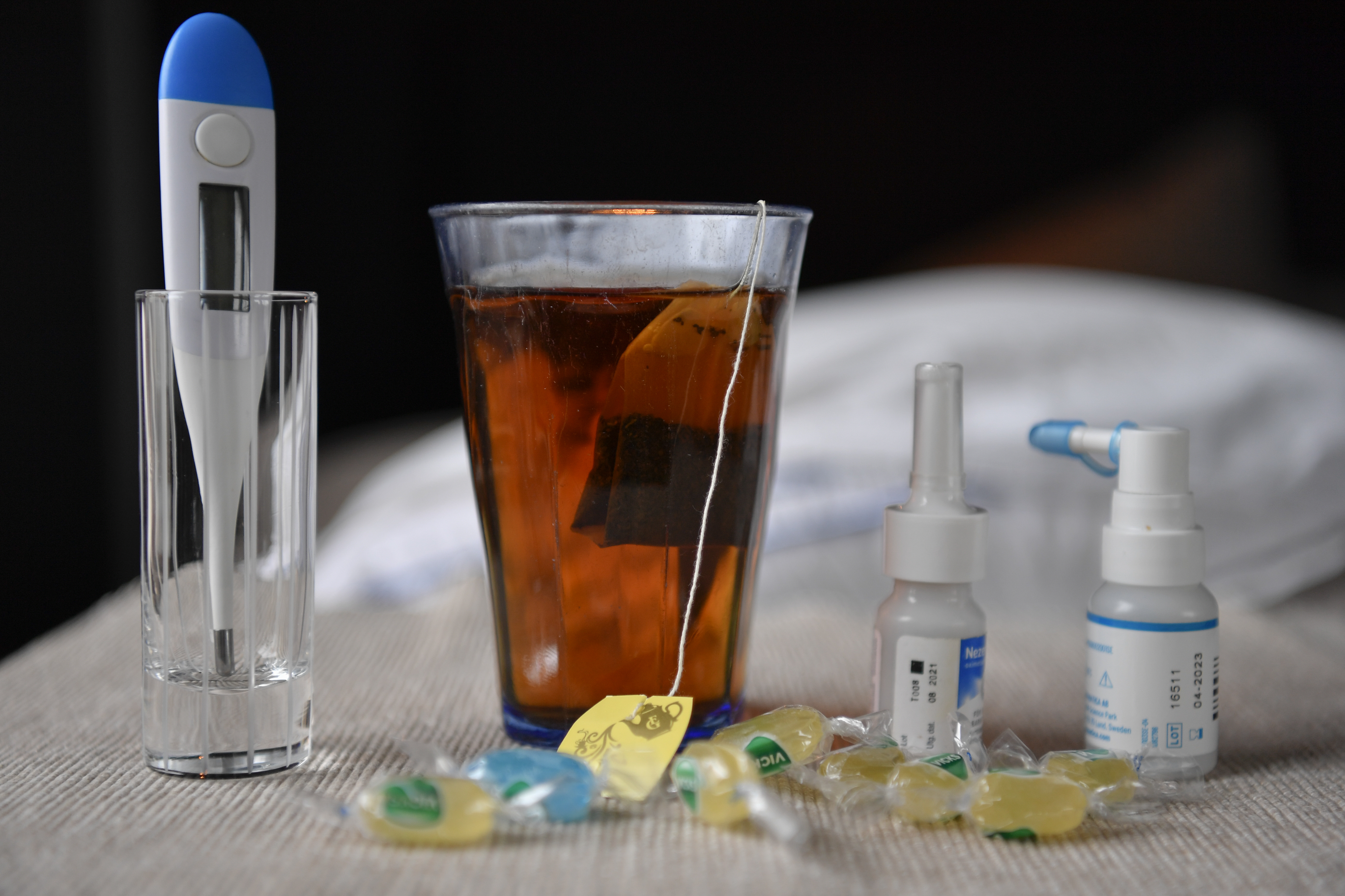 Febertermometer, ett glas te, mediciner och halstabletter.