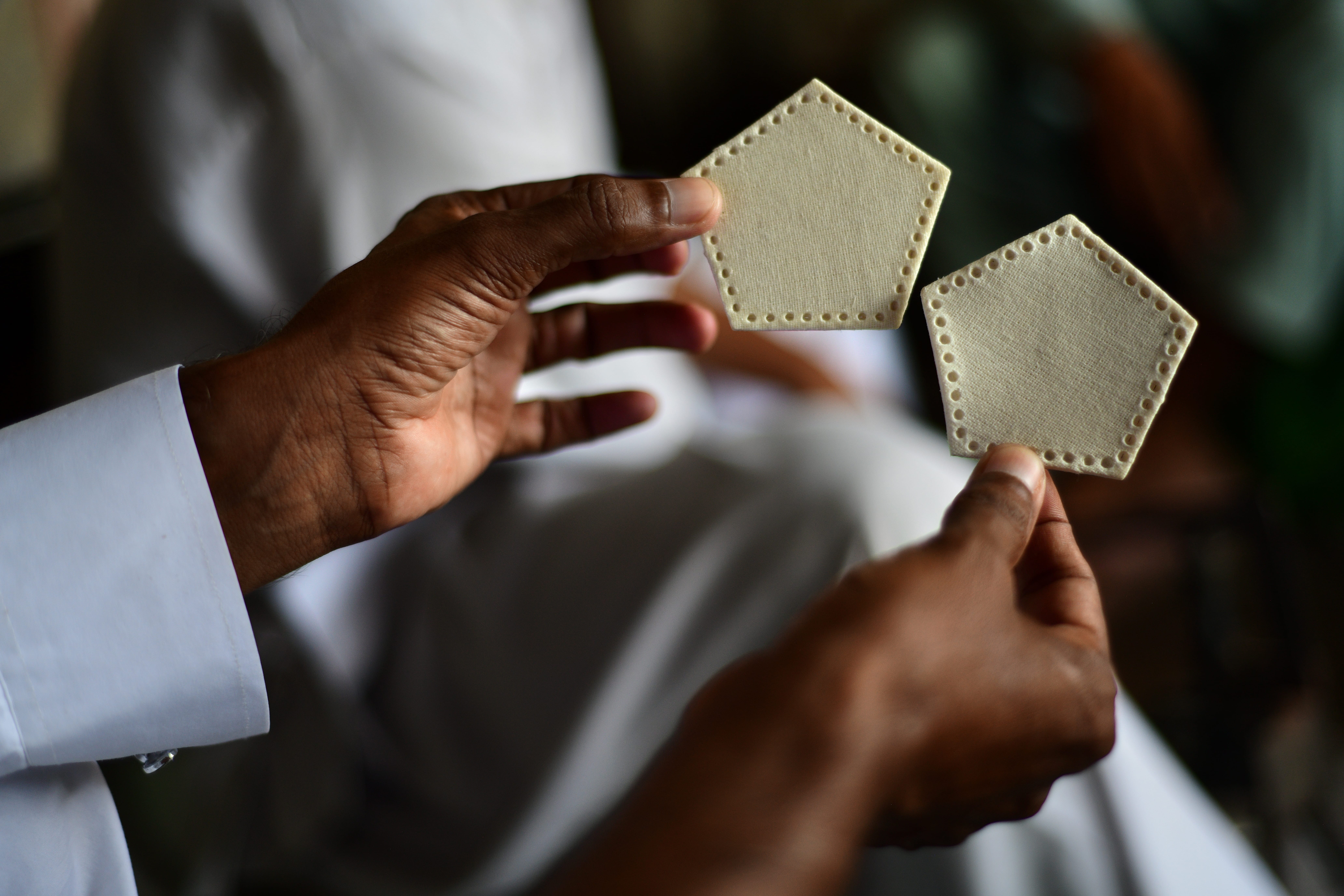 Bild på en man som håller upp två av de lappar som ska sys ihop till en fotboll.