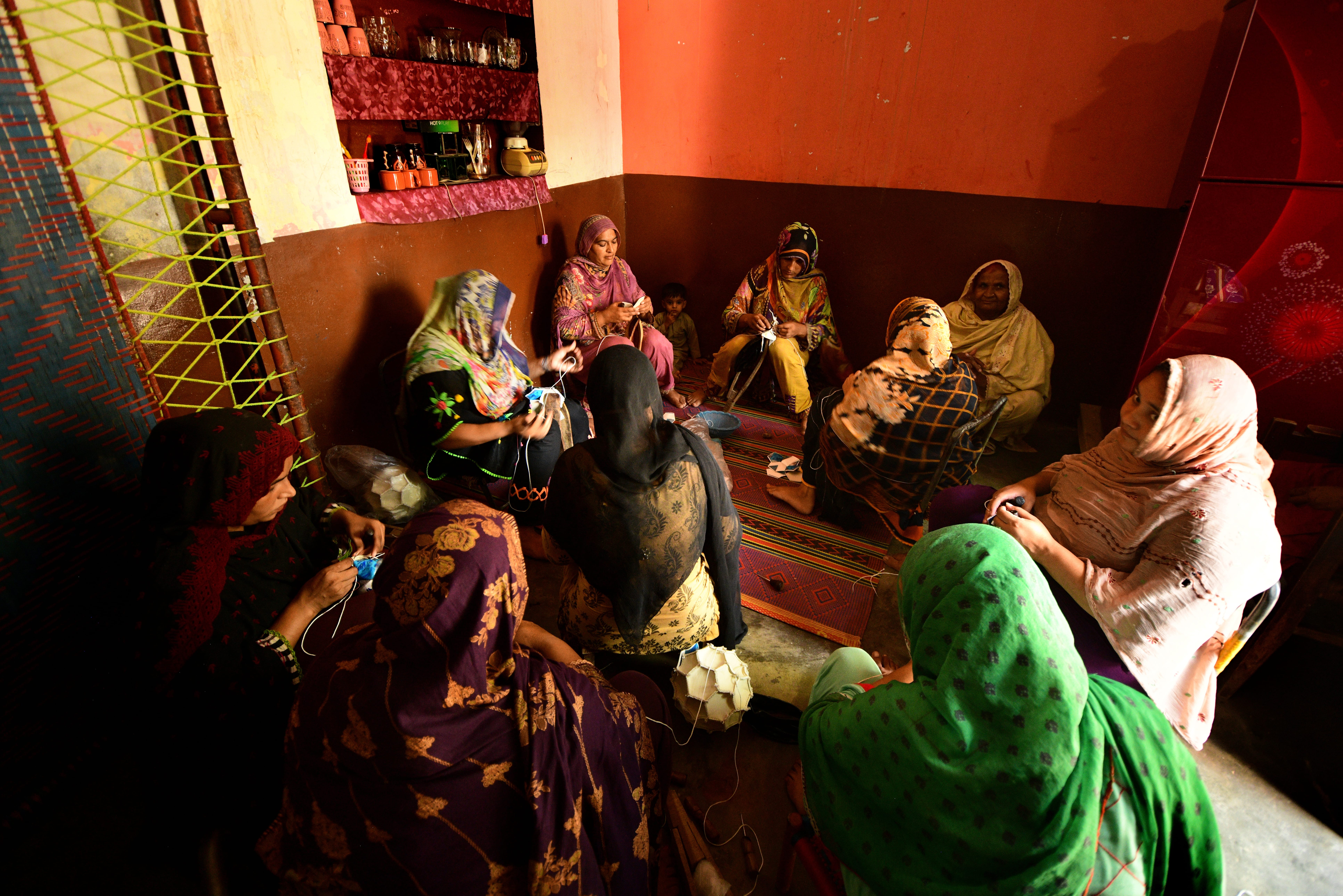 Bild på tio kvinnor som sitter i en ring och syr bollar.