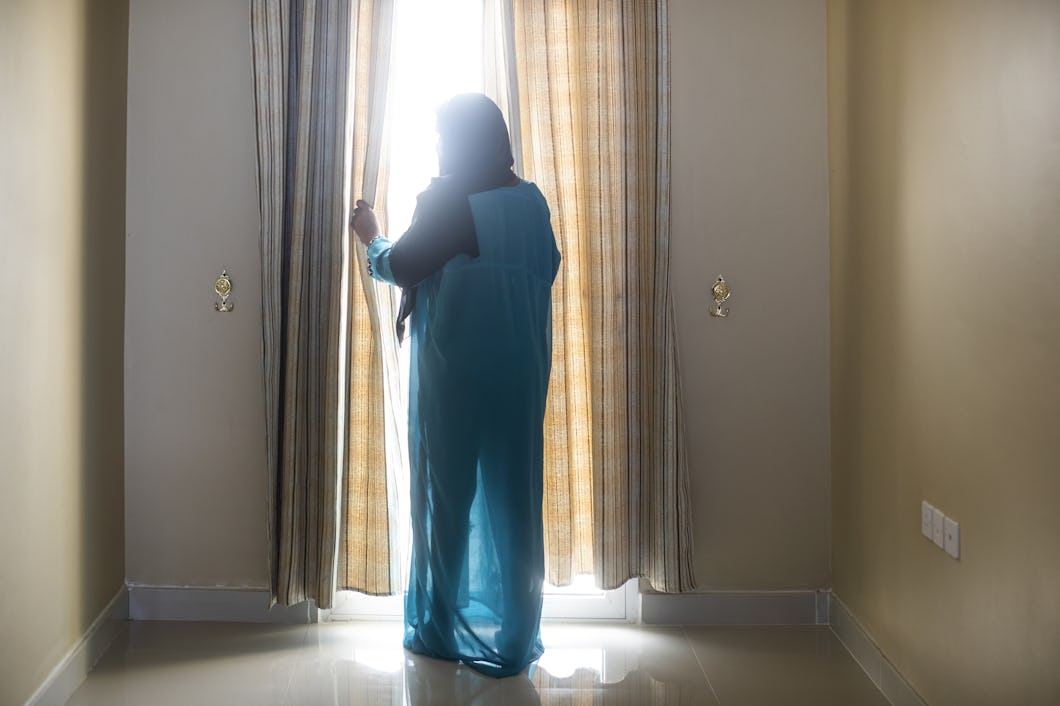 En afrikansk kvinna som utsatts för trafficking står framför ett fönster.