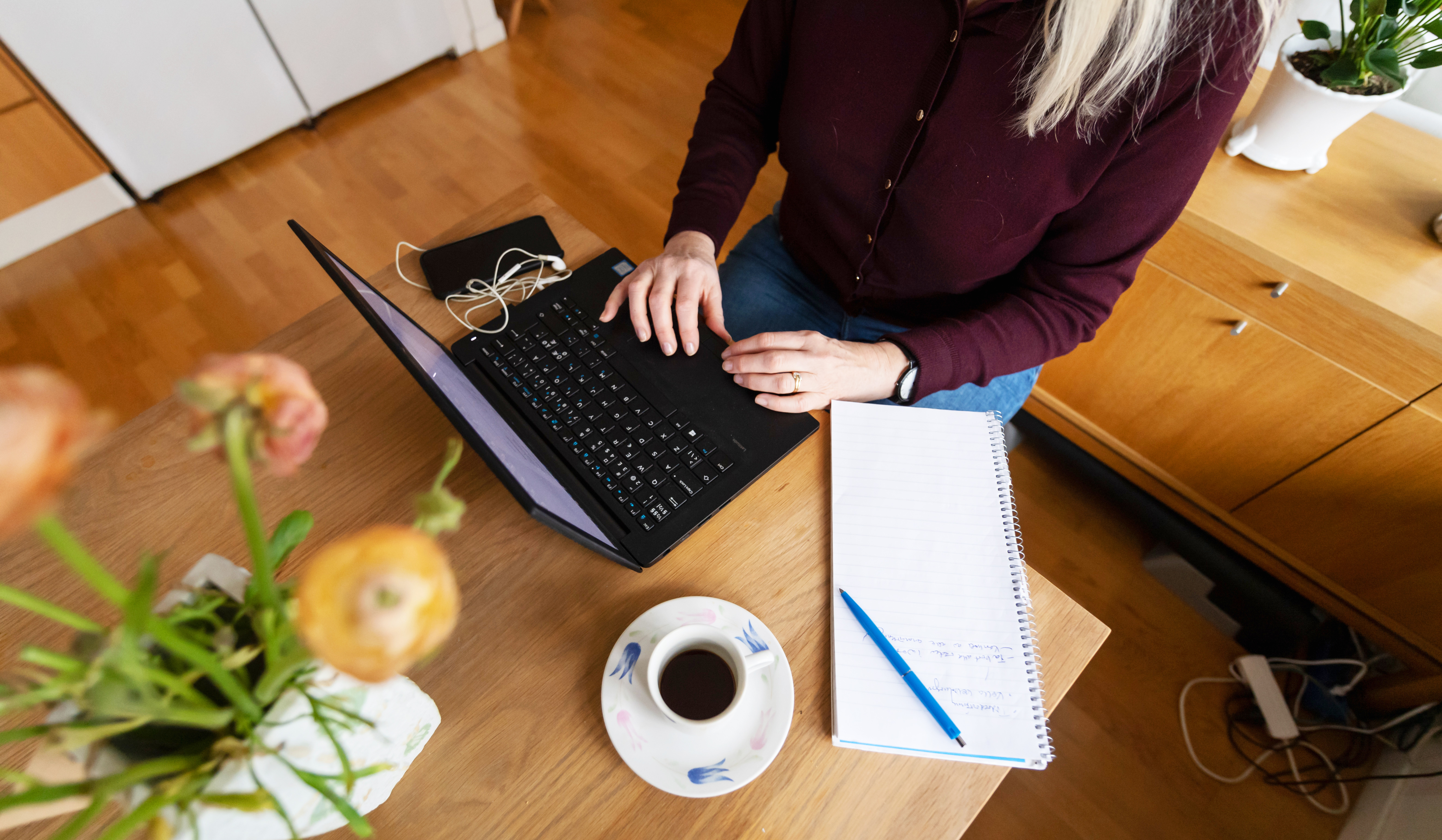 Kvinna skriver på dator och på block
