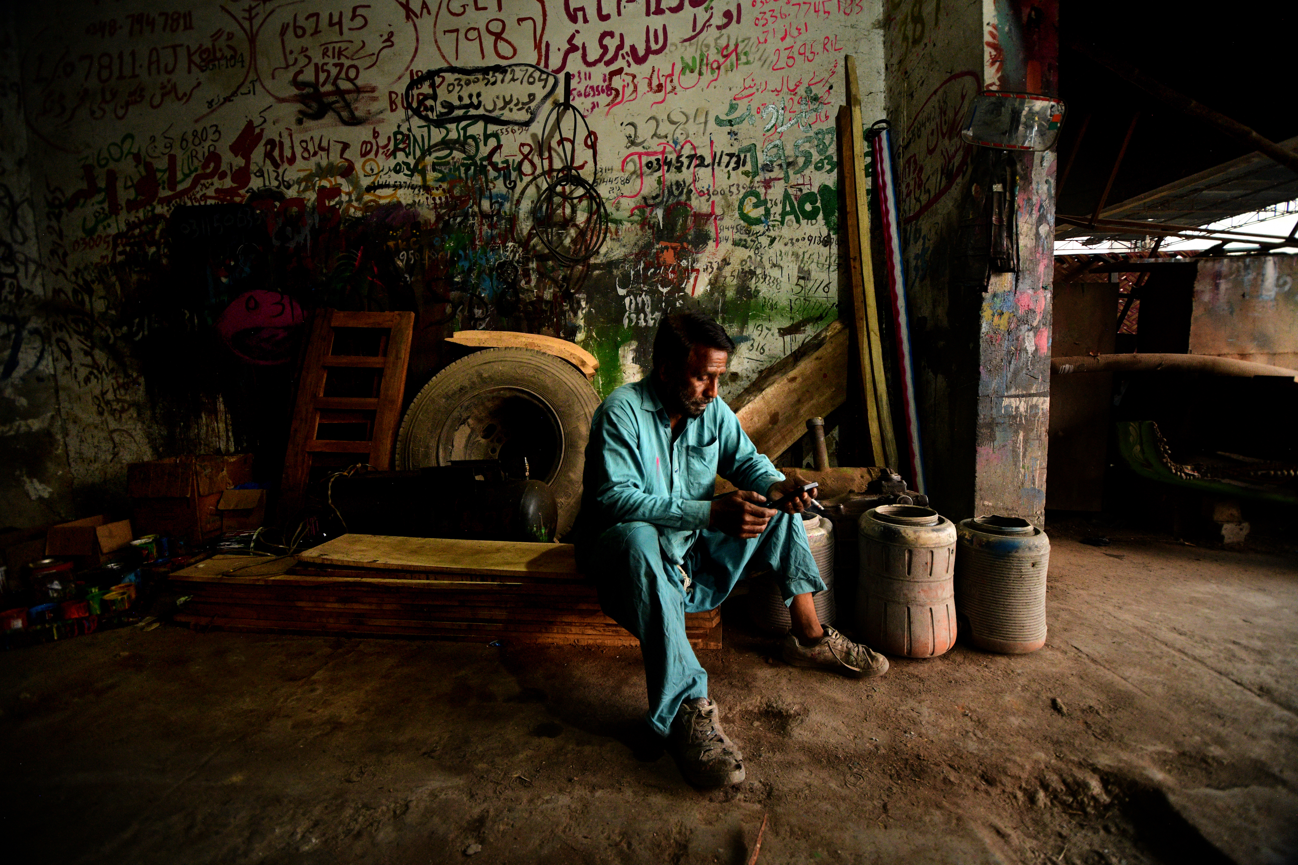 En målare sitter i en verkstad med registreringsnummer på väggarna.