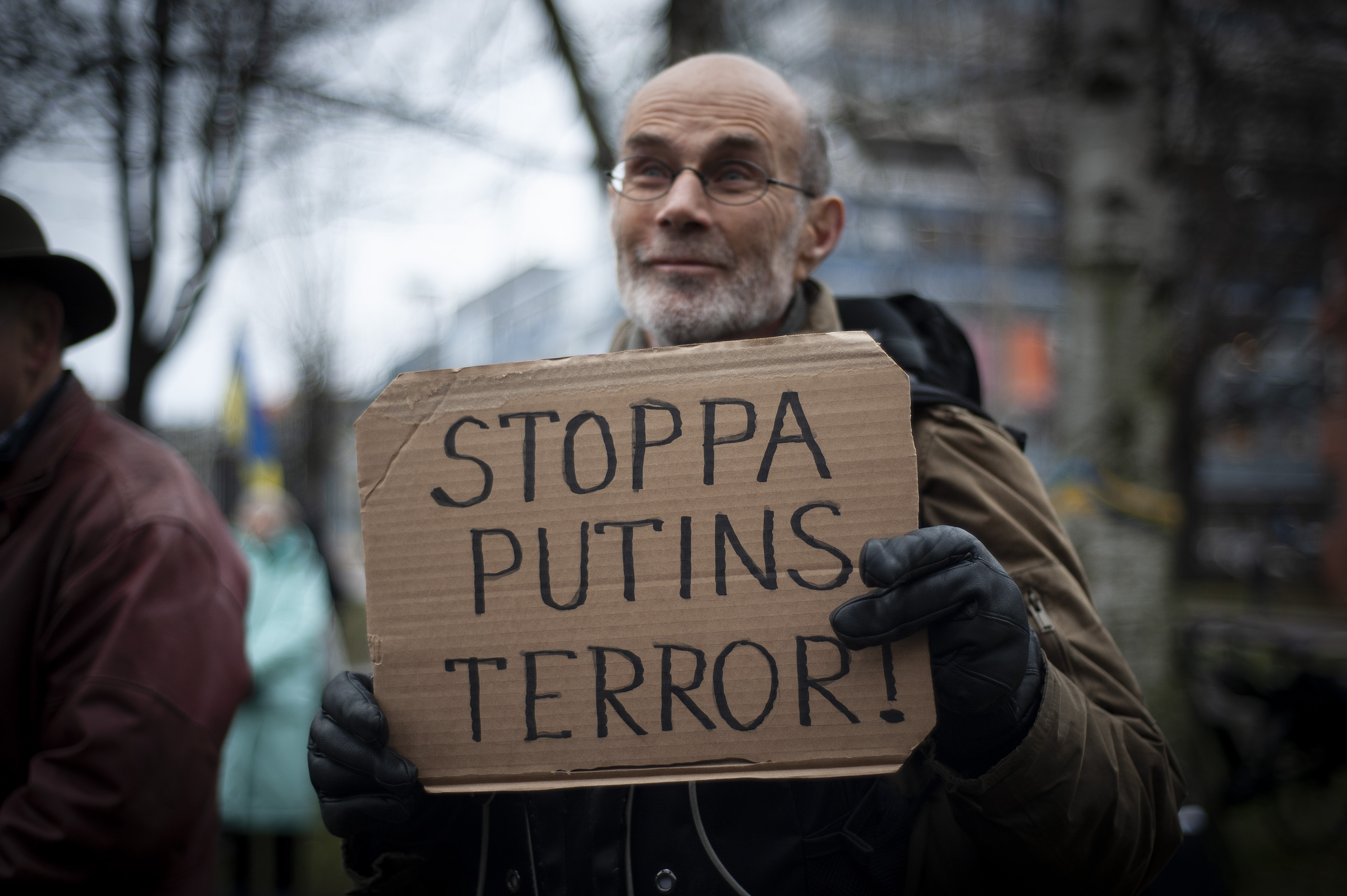 En man håller en skylt med texten "Stoppa Putins terror" på en manifestation för Ukraina.
