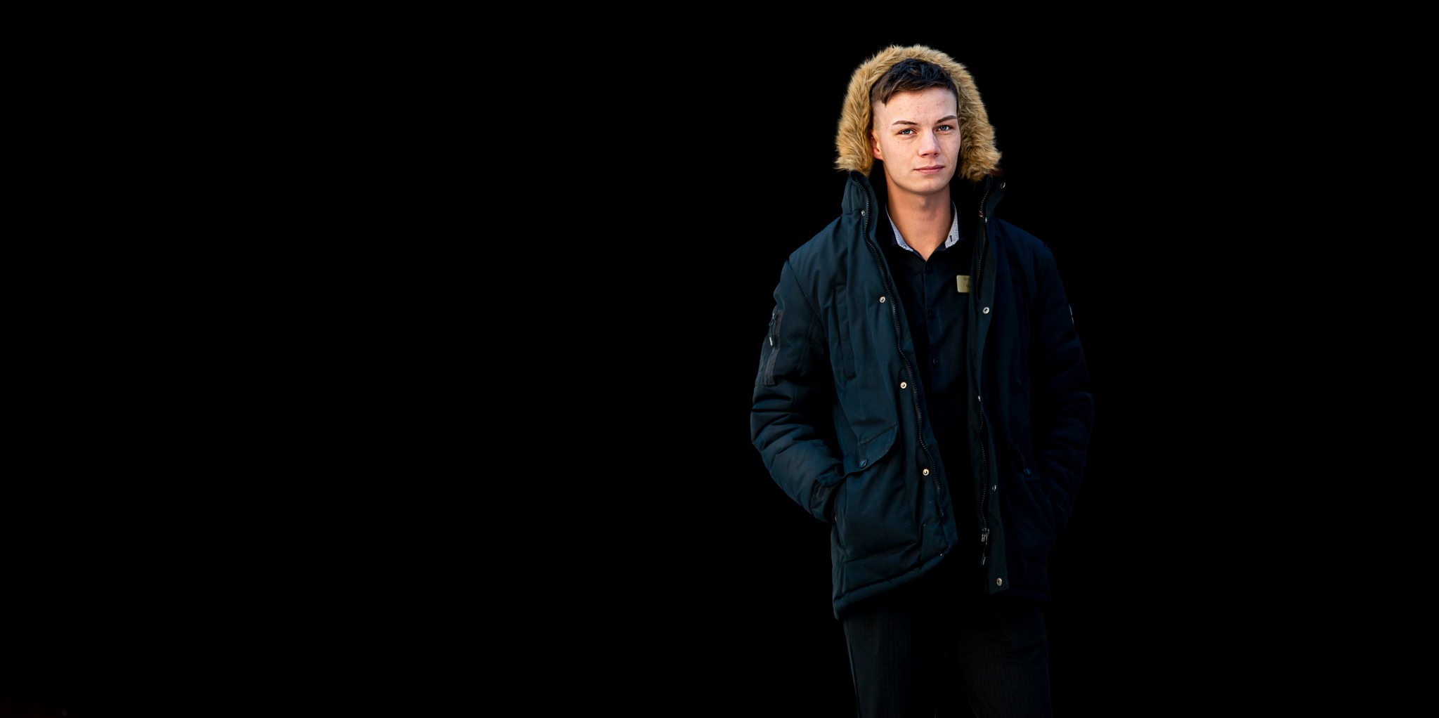 Gustav kollar in i kameran med jackans luva uppfälld över huvudet.