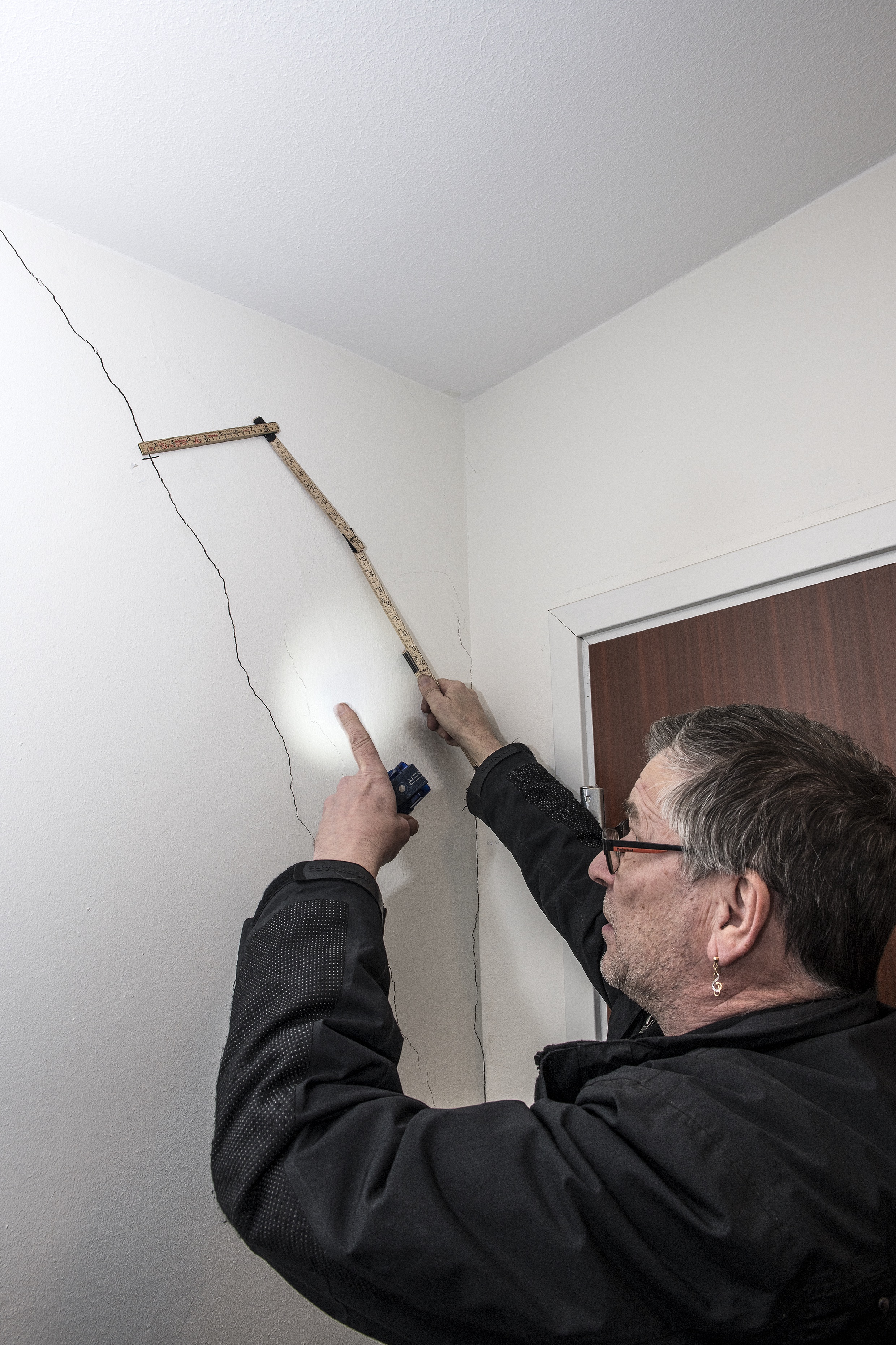 Drifttekniker Anders Salomonsson på Riksbyggen i Kiruna mäter en spricka i trappuppgången.