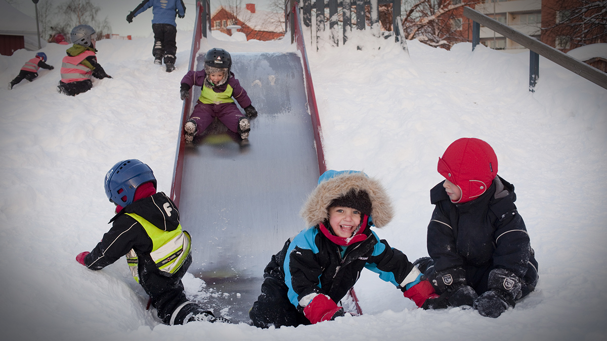 Barn leker utomhus i snön på förskola.