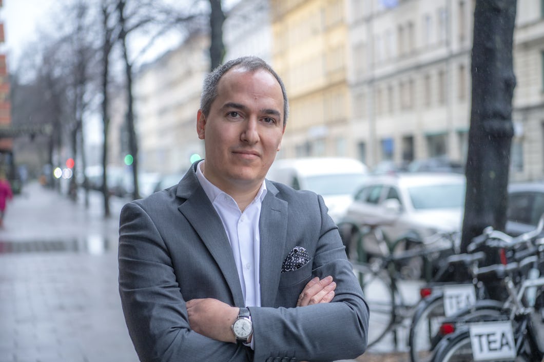 Pierre Sandberg i grå kostym och ljus skorta, framför stadsmiljö i oskärpa.