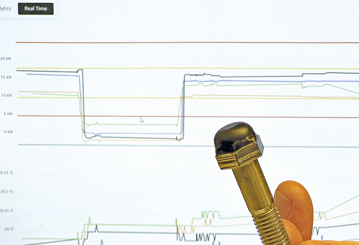 Datorskärm med diagram, och framför den en skruv.