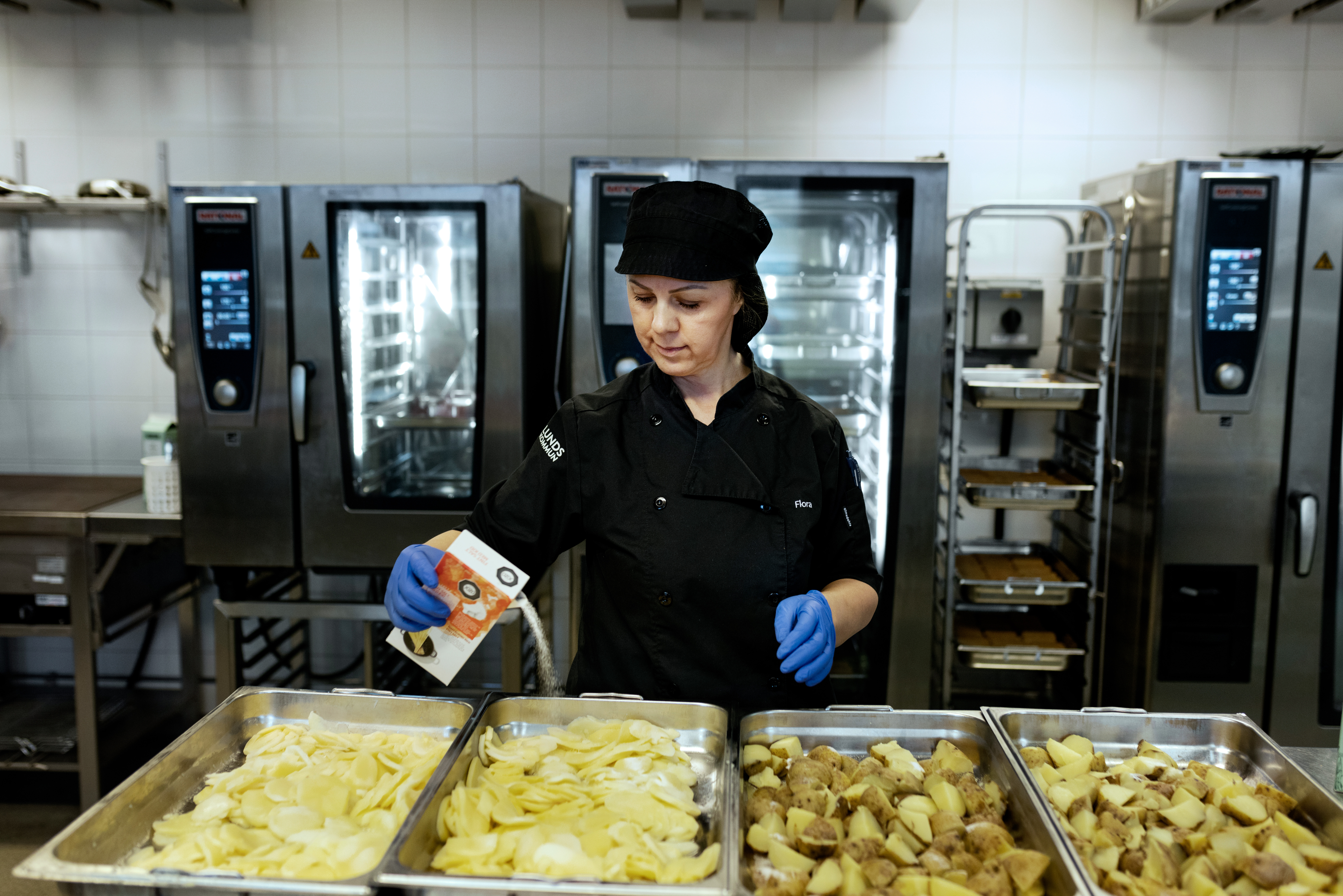 Flora Shahini förbereder rå potatis och gårdagens kokta potatis för ugnen.