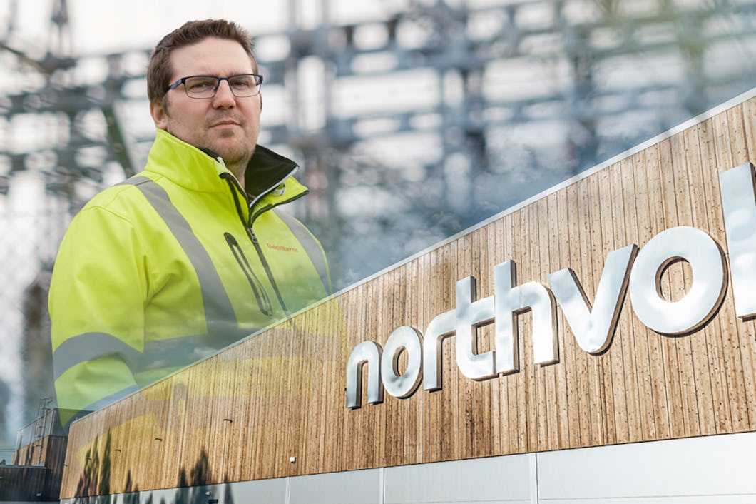 Mathias Hansson monterad tillsammans med Northvolts logga på deras vägg.