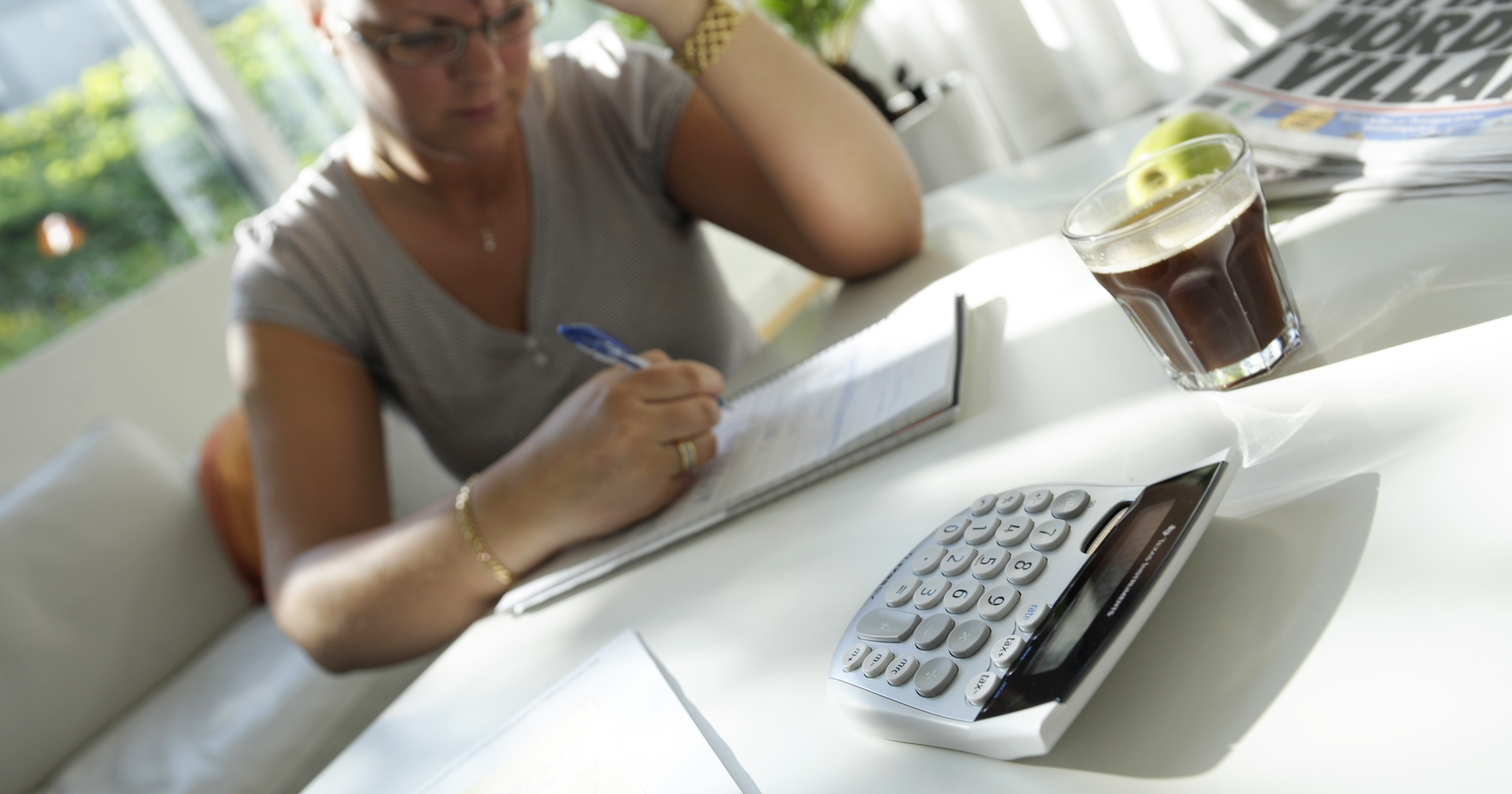 Kvinna sitter vid bord och räknar med miniräknare