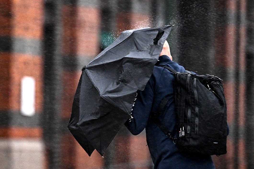 Man med paraply som skydd mot regn på tvären.
