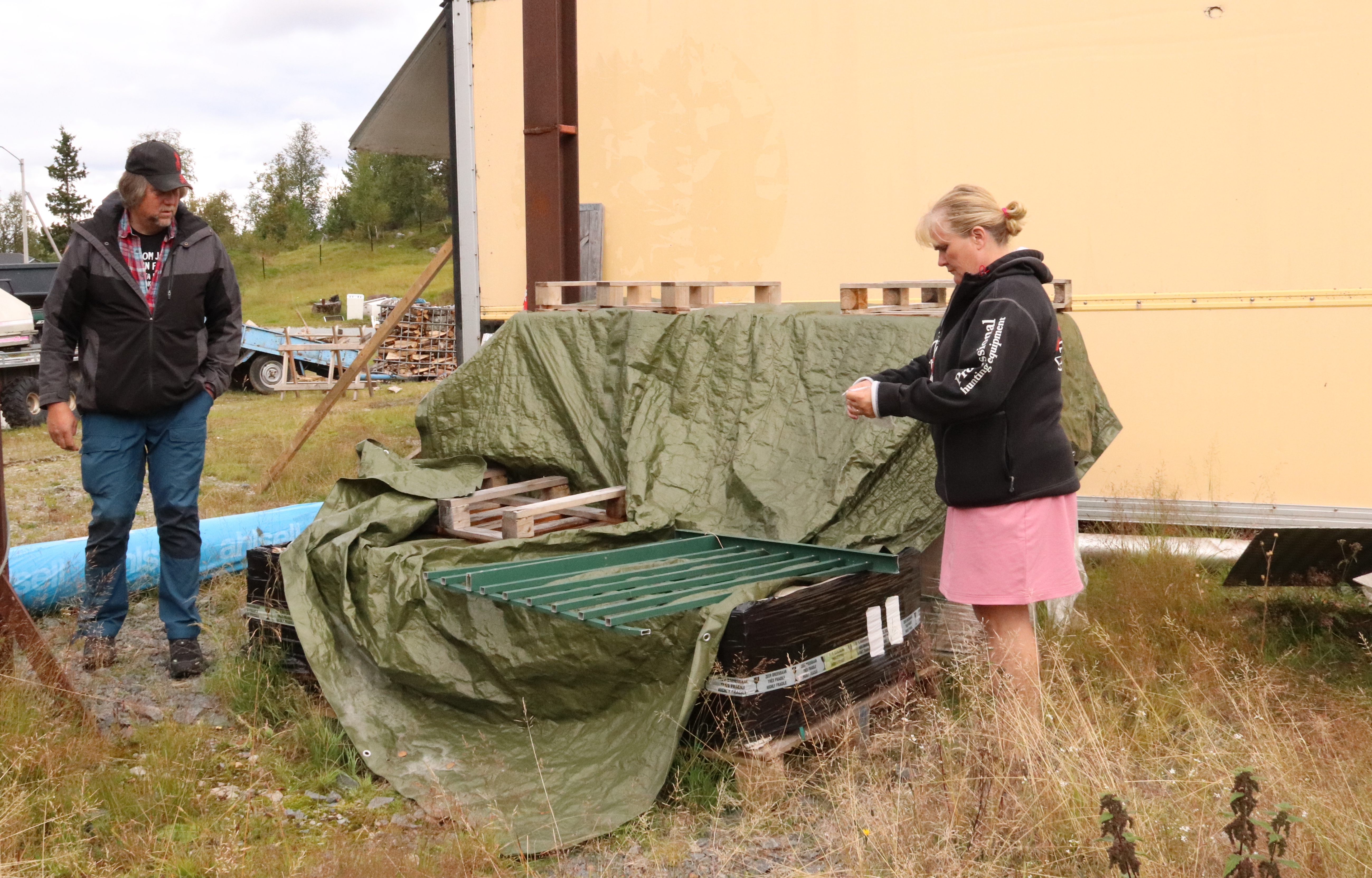 Jan och Lotta på gården intill en pall med solcellspaneler.