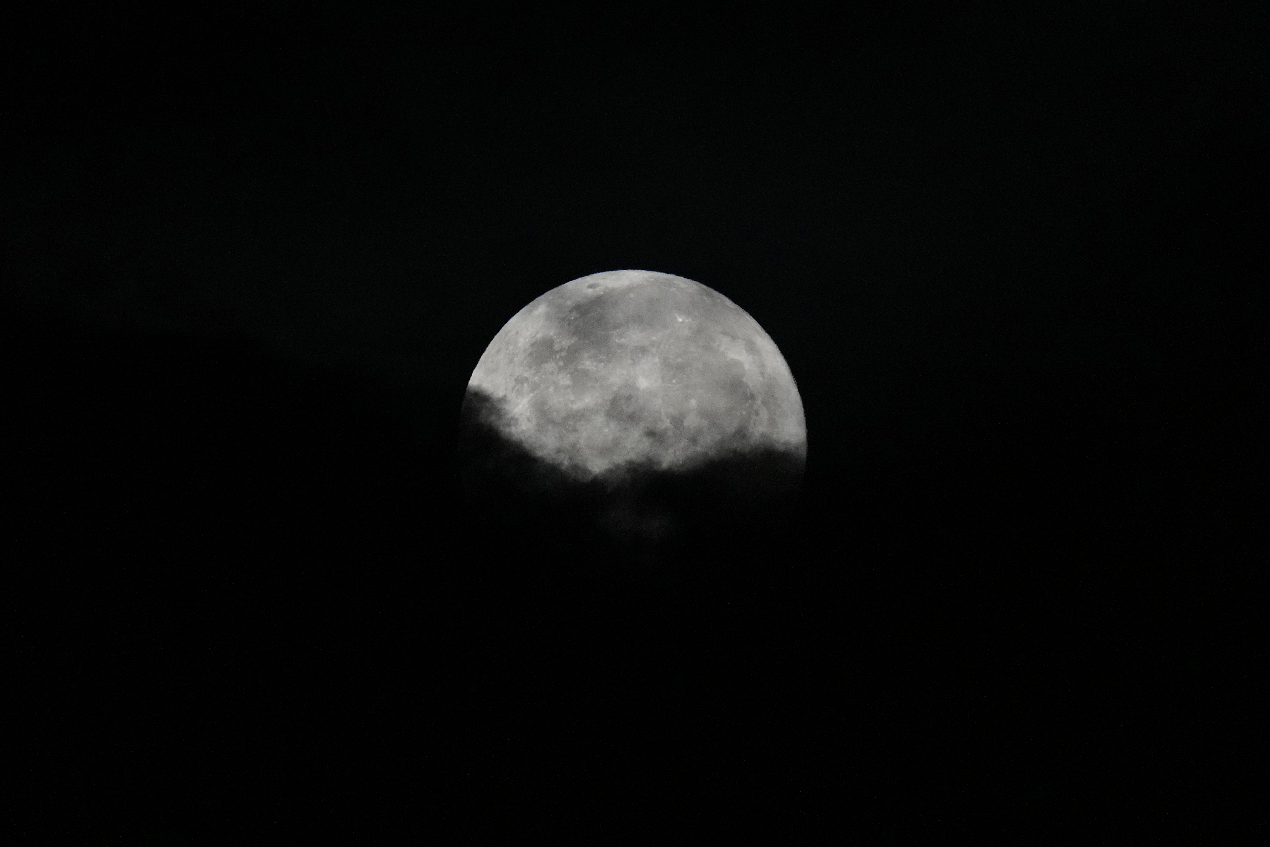 En måne syns på mörk himmel