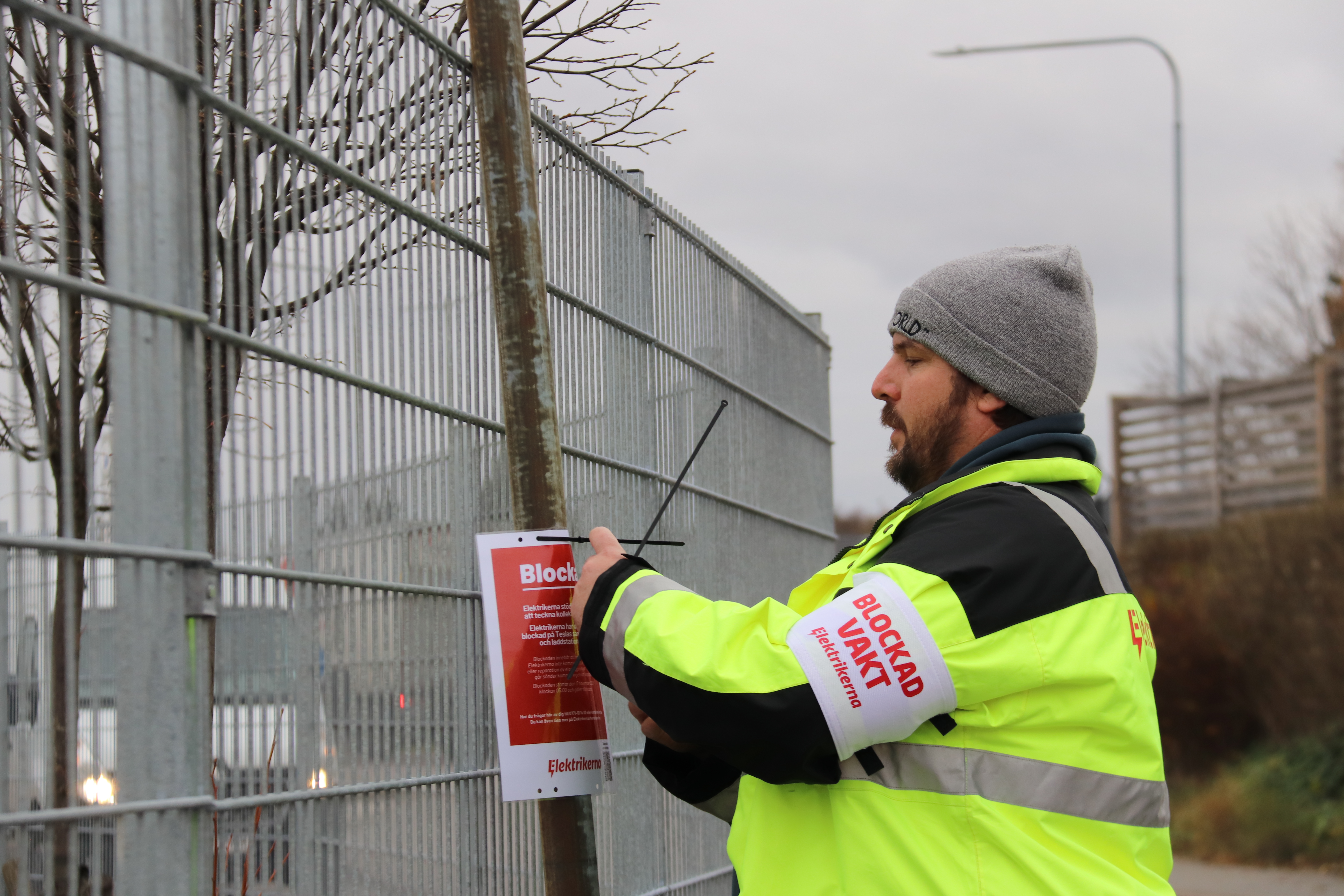 Jens Hansson, ombudsman Elektrikerna, sätter upp blockadskylt utanför Teslas verkstad i Segeltorp.