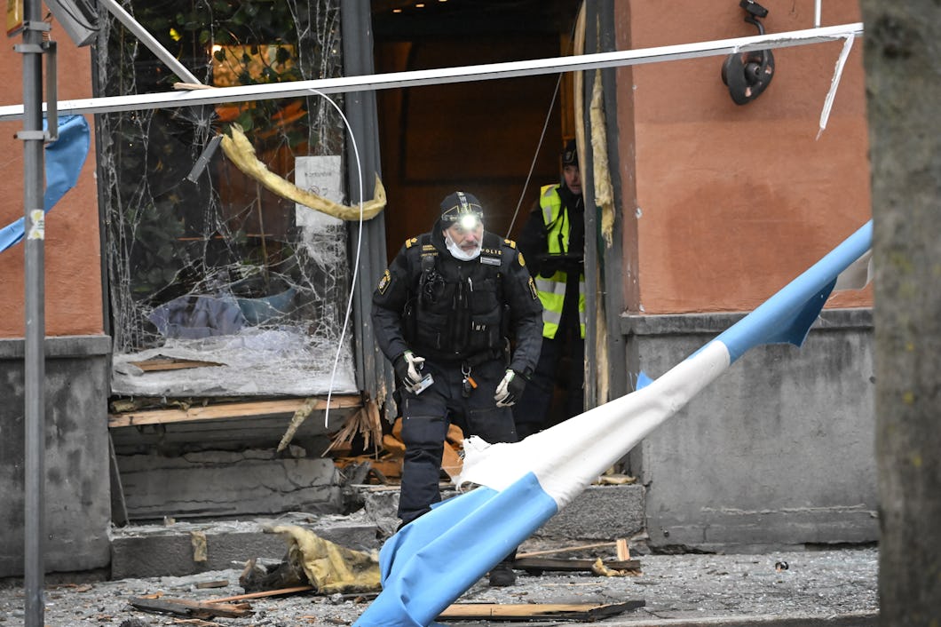 En polis undersöker resterna av en sprängd entré på Södermalm i Stockholm.