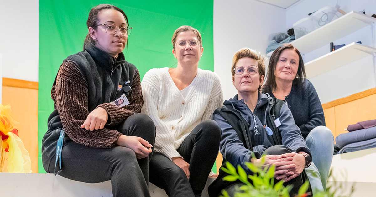 Fyra pedagoger sitter på en bänk framför en grön skärm.