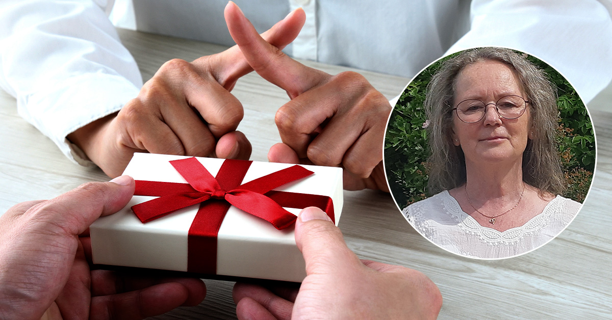 En kvinna håller en presentask med ett rött band.