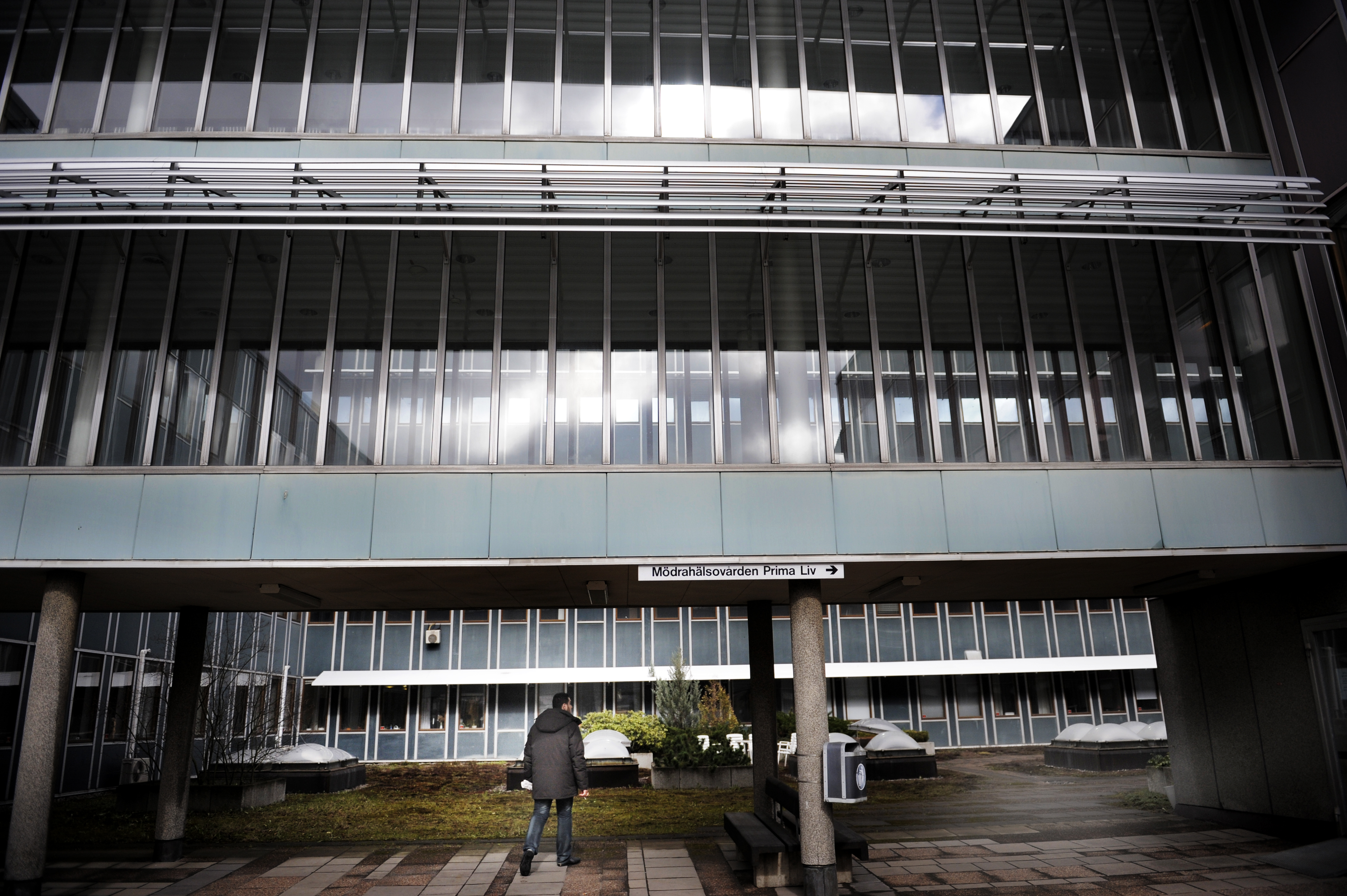 En person som går på en trottoar framför en byggnad.