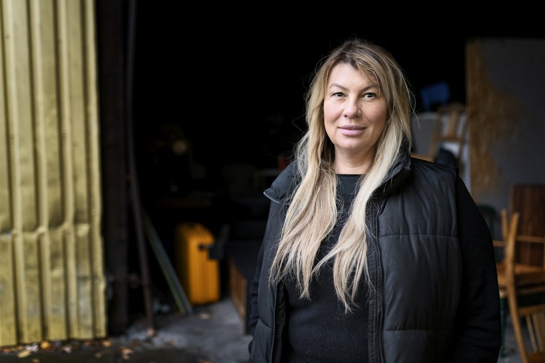 Malin Enström står framför byggnaden Ladan. I bakgrunden skymtar gamla möbler.