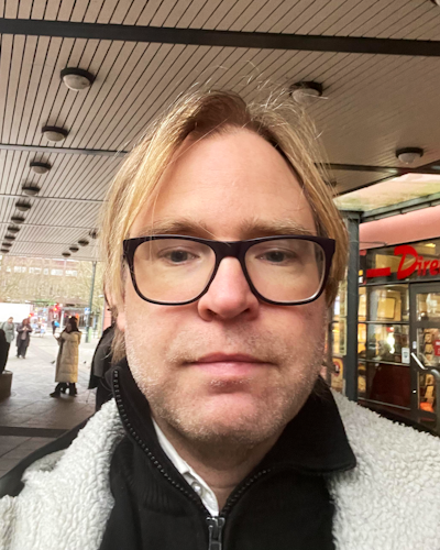 Richard Ströberg, busschaufför, i glasögon framför en butik.