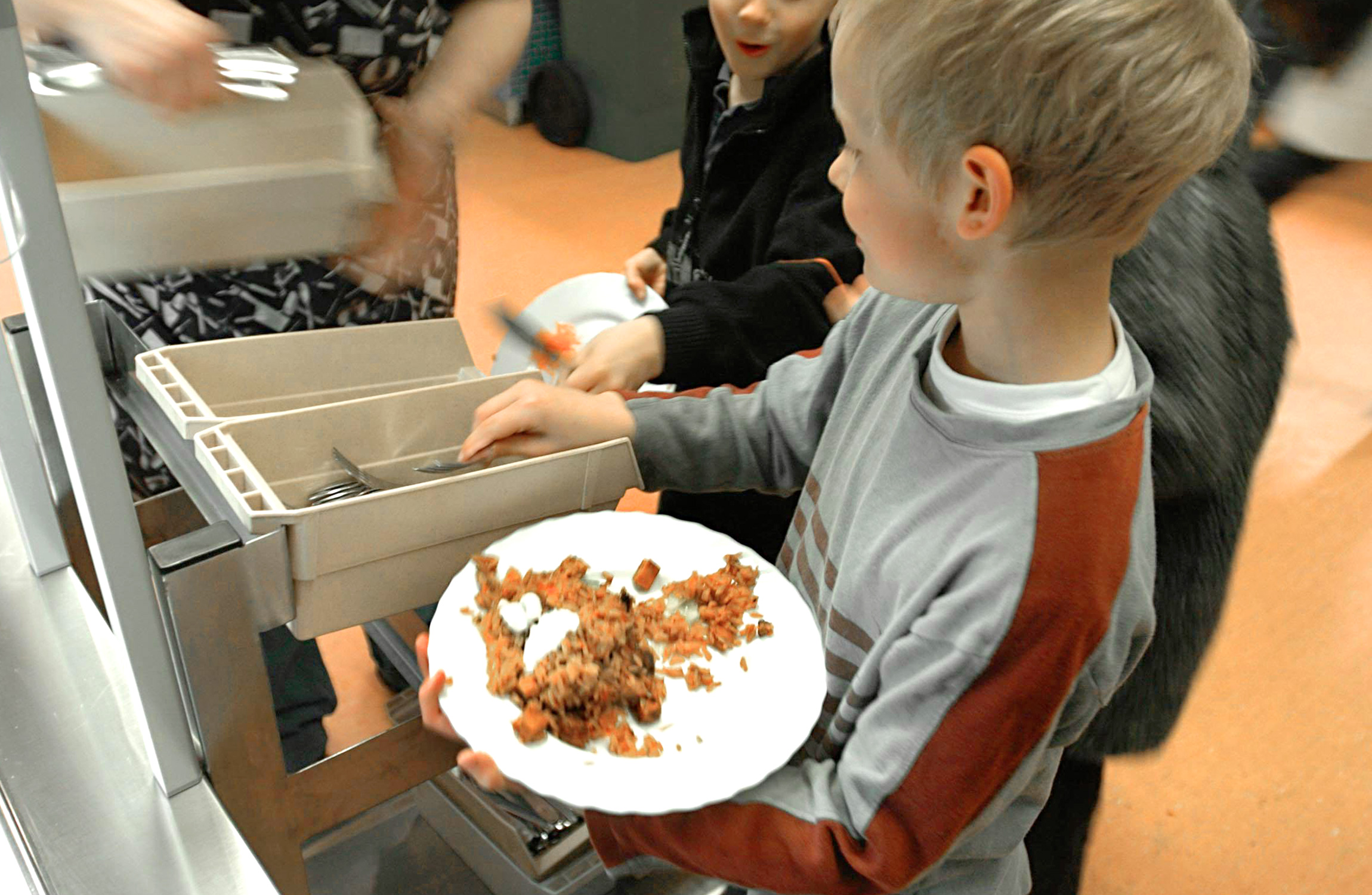 En pojke som håller en tallrik med mat.