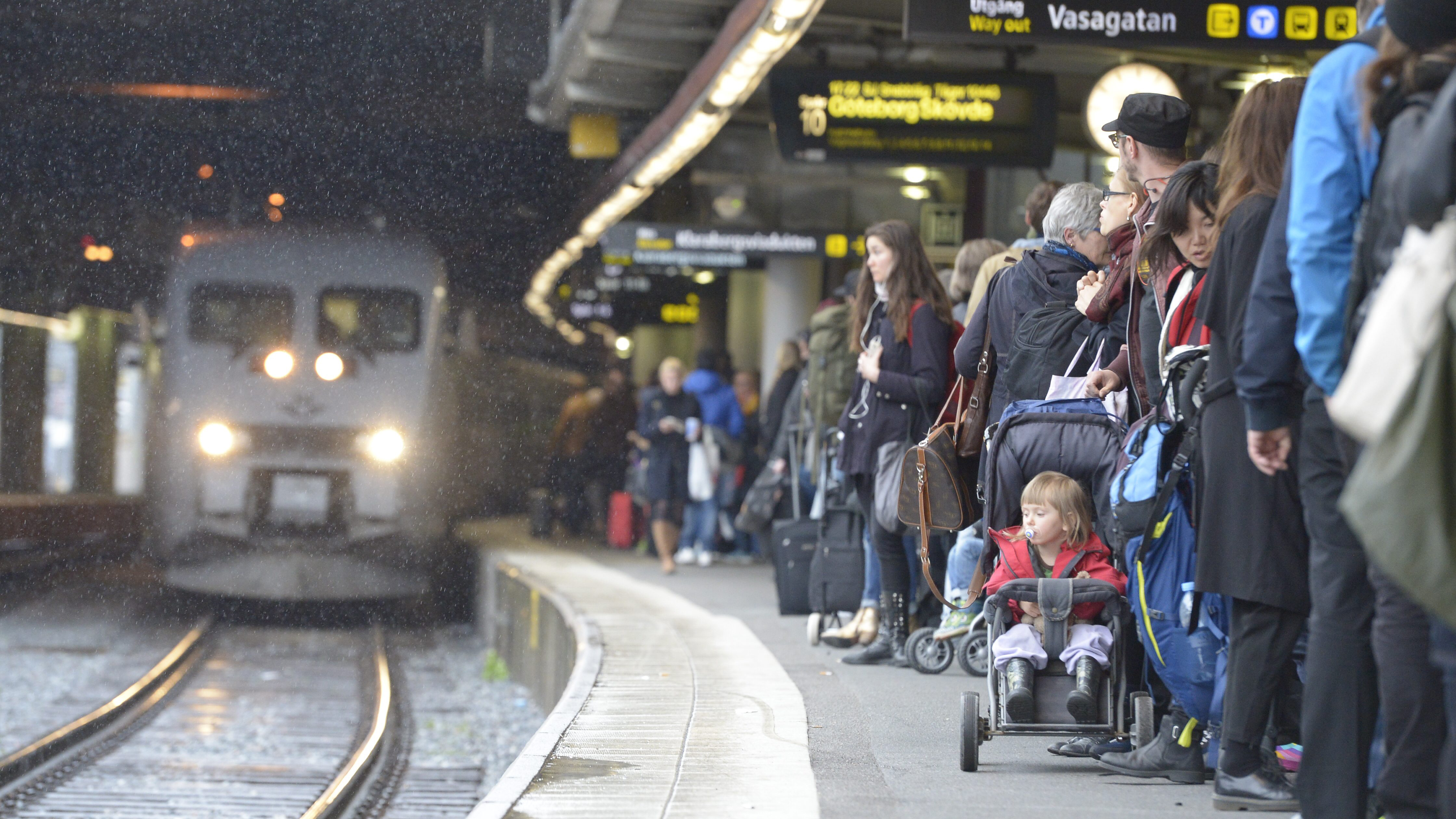 En grupp människor som väntar på att få gå ombord på ett tåg.