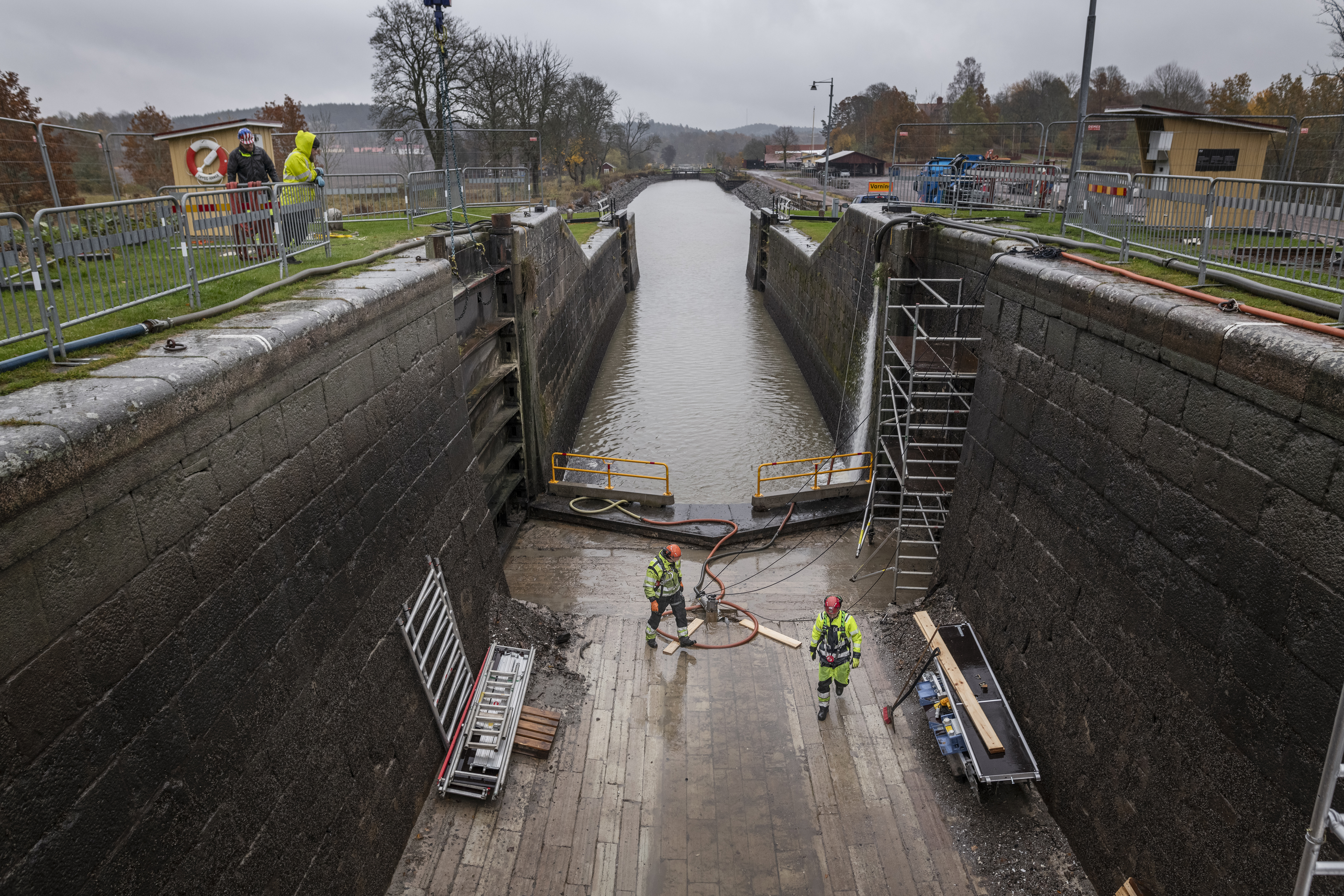 Översiktsbild från en sluss där slussporten är borttagen med två arbetare i arbetskläder.