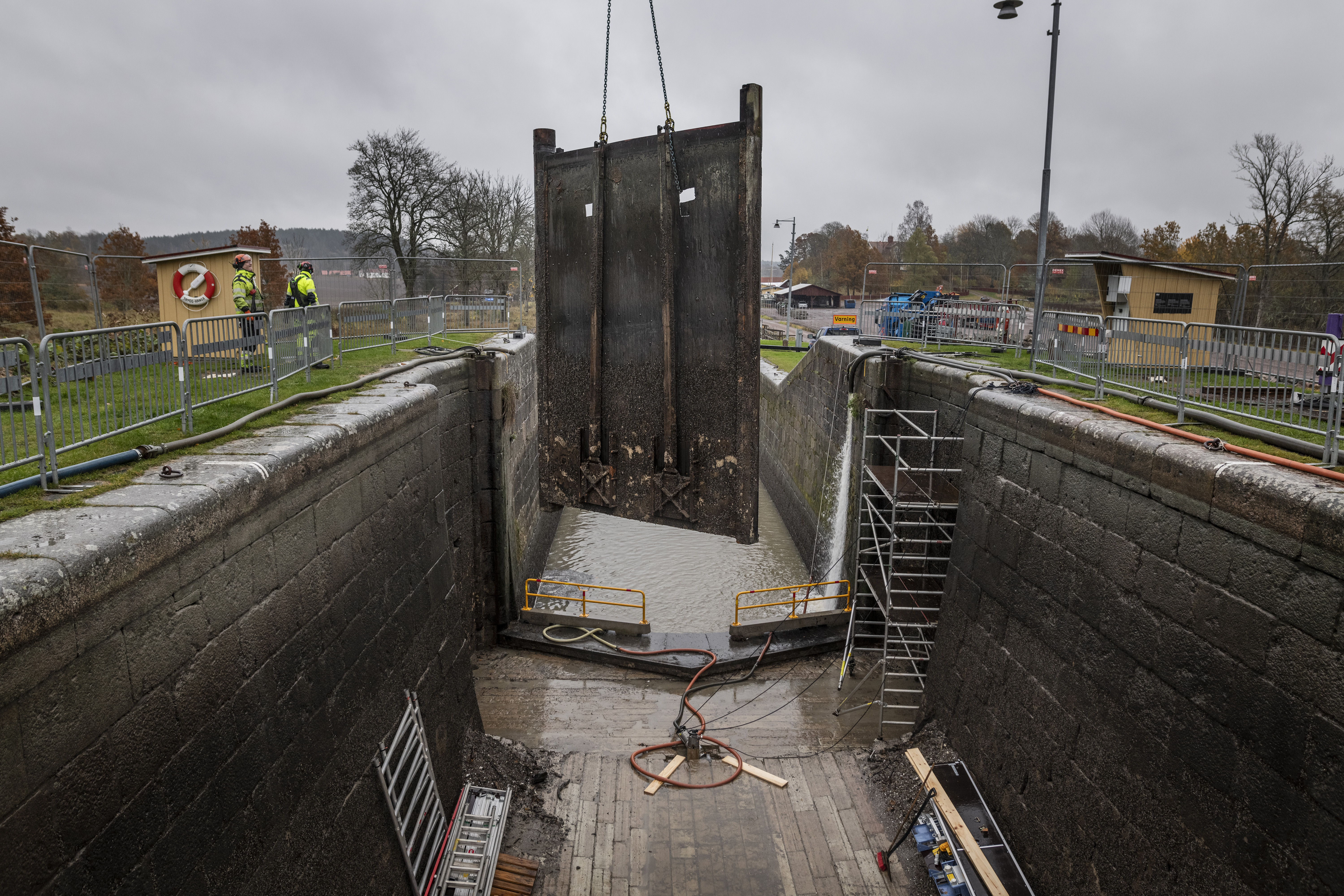 En stålslussport lyfts från sin plats i kedjor.