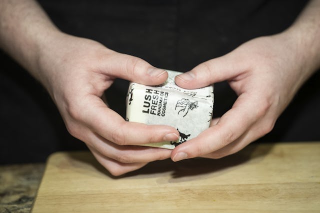 En persons händer som håller en vara på en skärbräda.
