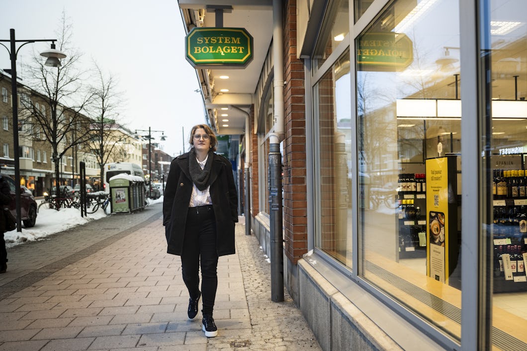 En person som går på en trottoar framför en butik.