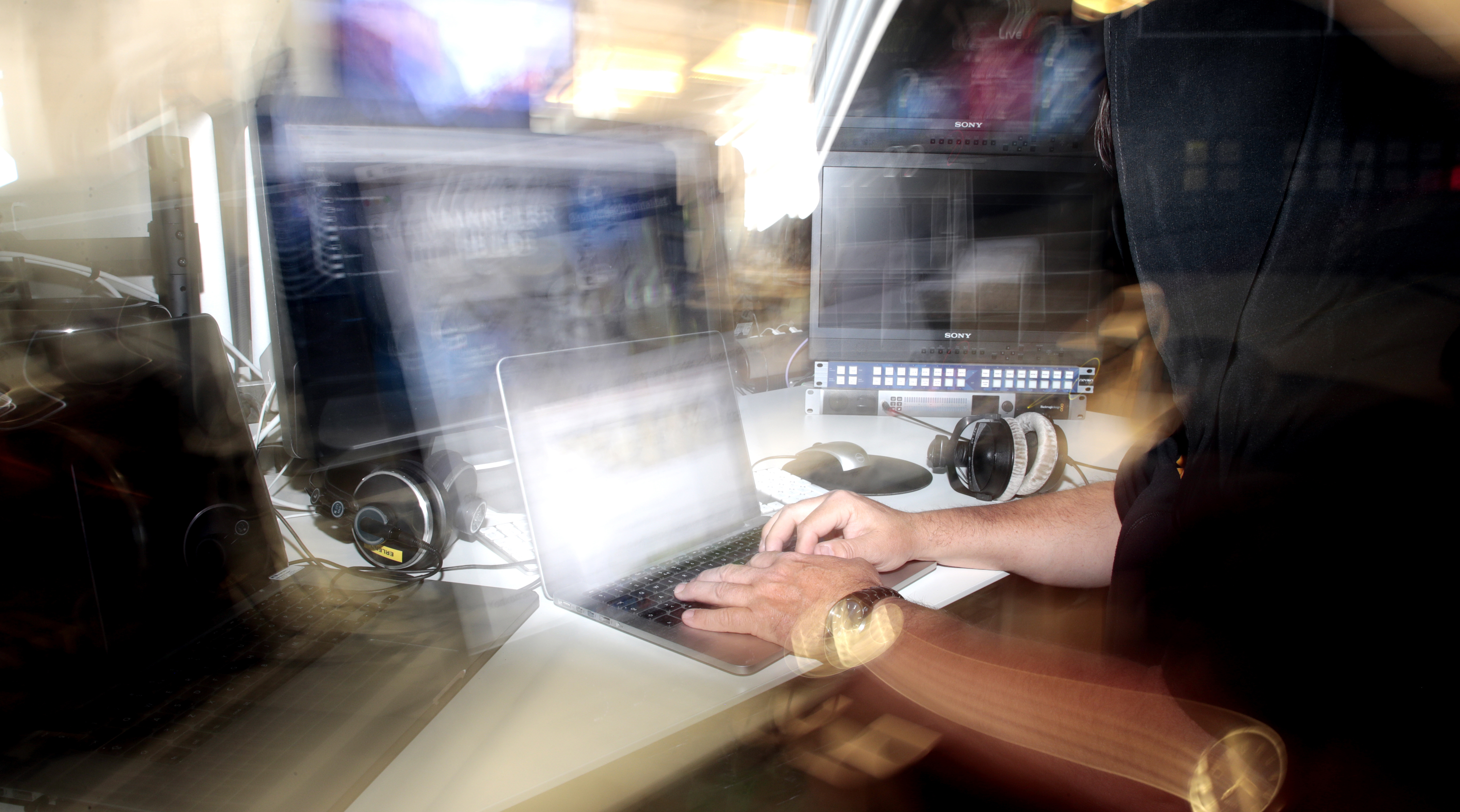 En man i en svart luvtröja som arbetar på en bärbar dator.