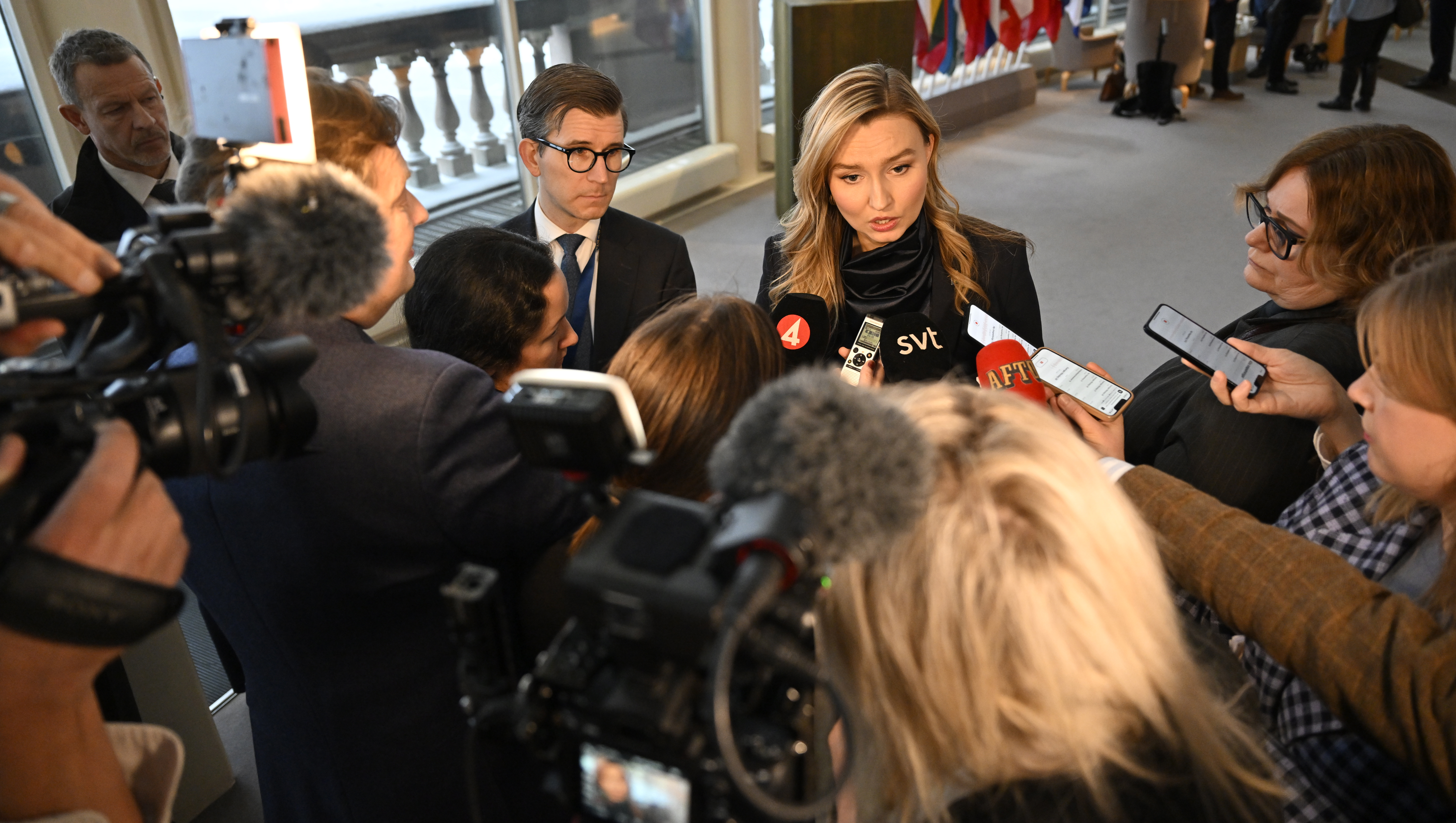 En kvinna är omgiven av reportrar och fotografer.