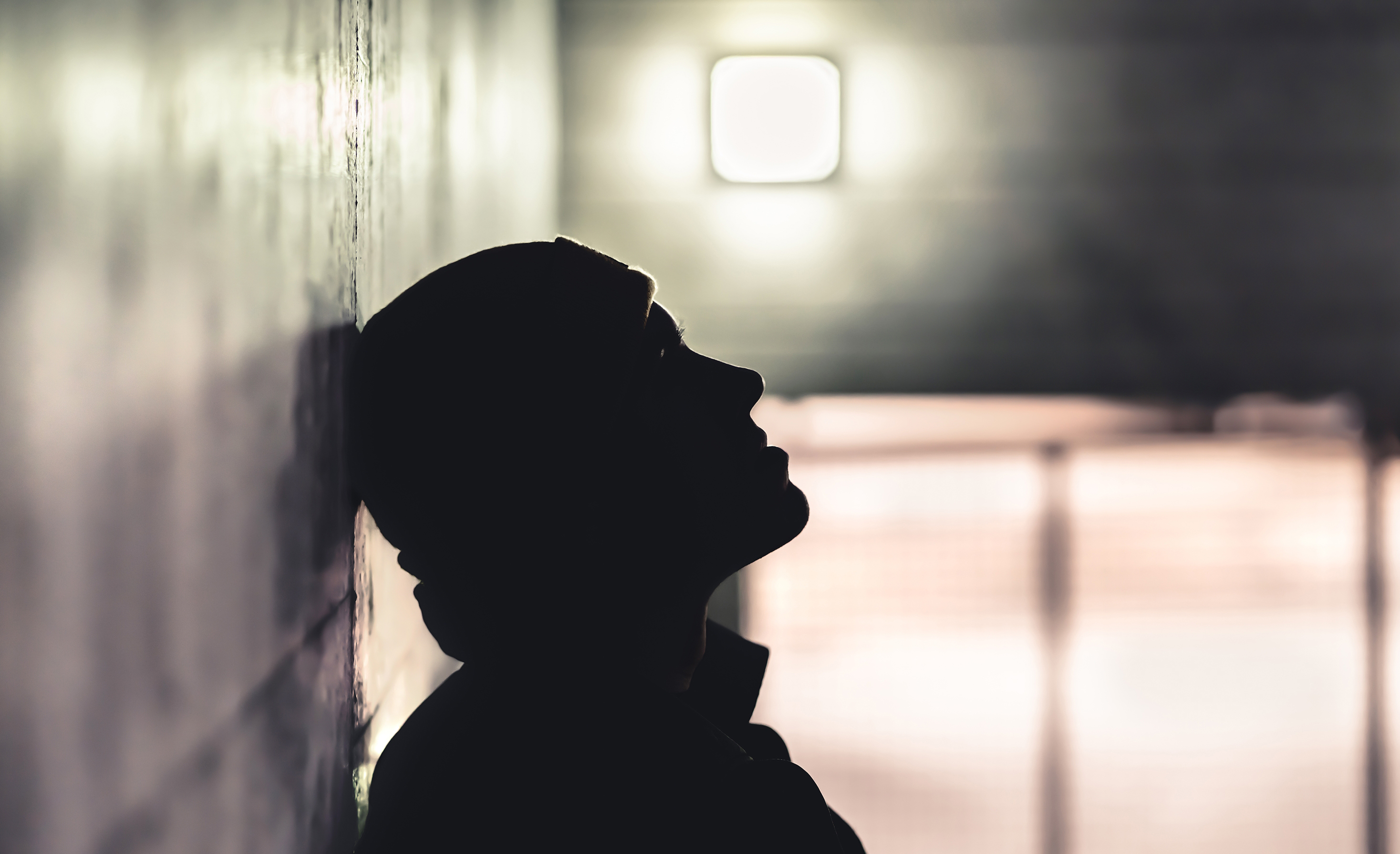En siluett av en person som lutar sig mot en vägg.