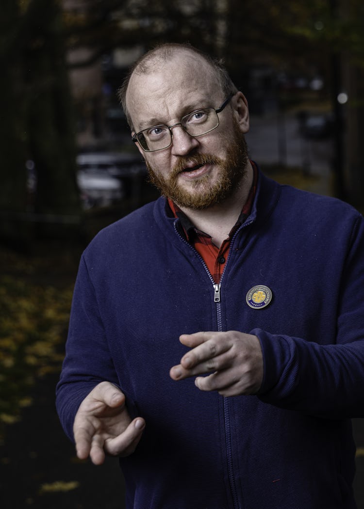 Kim Nilsson gestikulerar med händerna och pratar med en annan man som syns snett bakifrån.