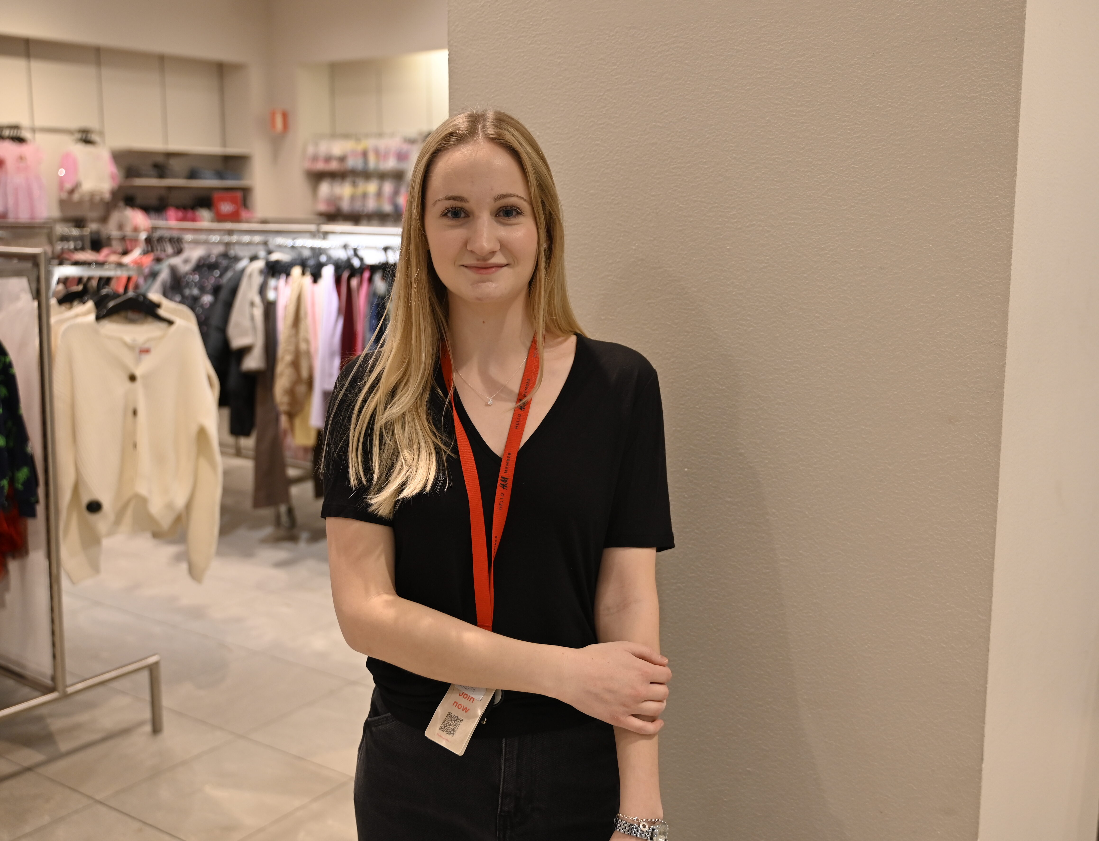 En ung kvinna som står framför ett ställ med kläder.