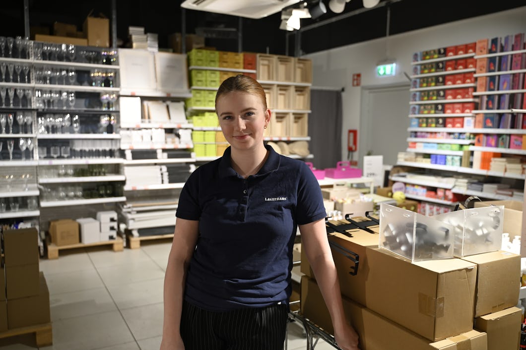 En kvinna som står i en butik med lådor.
