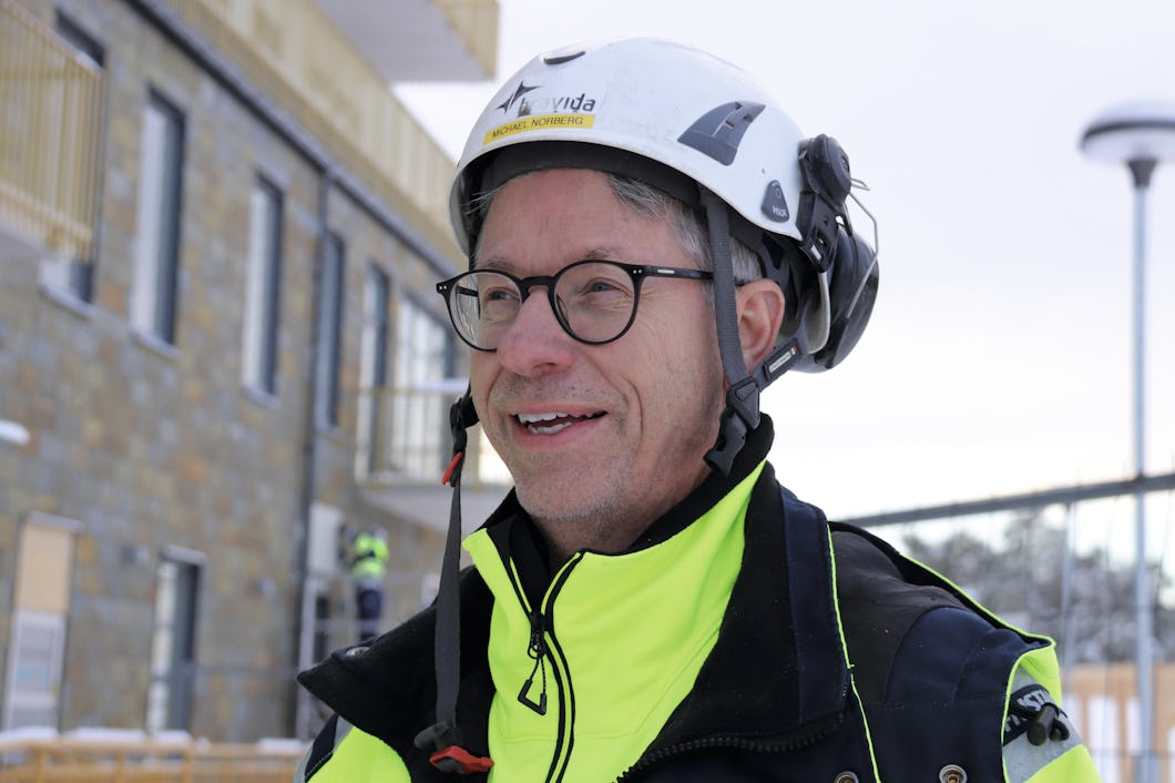 Michael Norberg som bär hjälm och glasögon framför en byggnad.