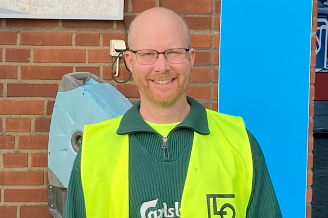 Peter Janson i en gul väst framför en tegelvägg.
