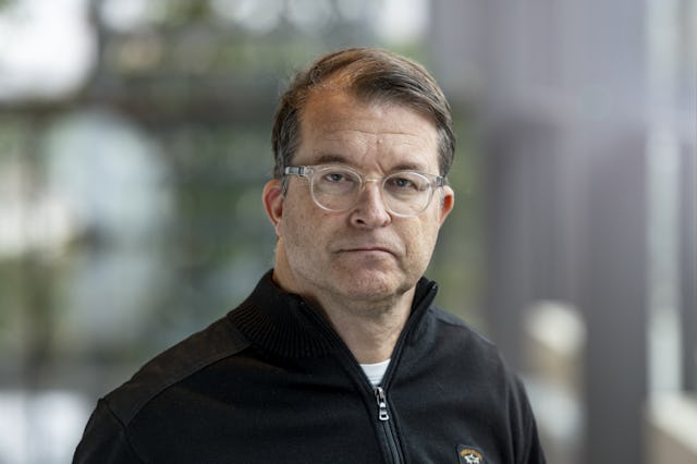 En man i glasögon som sitter framför ett fönster.