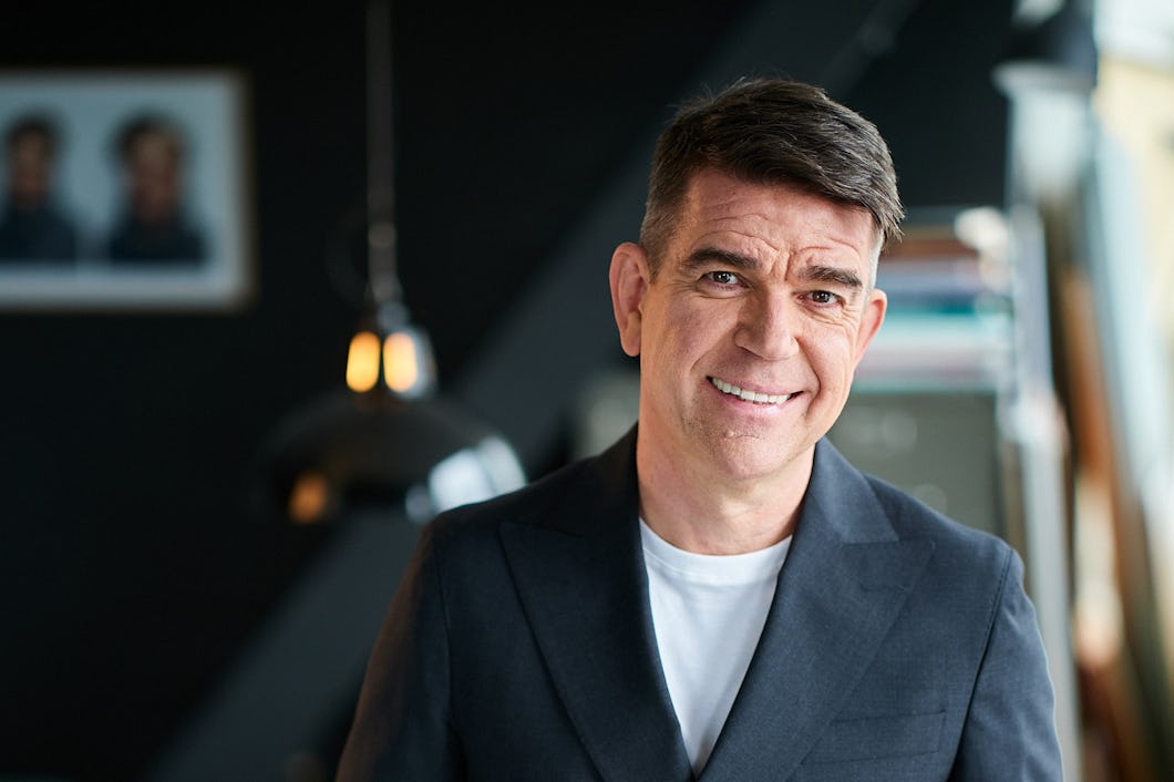 Patrick Ekwall i kostym ler på ett kontor.