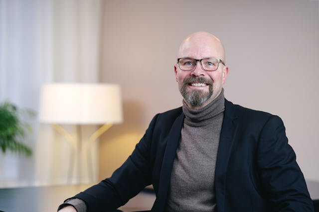 En skallig man i kostym som sitter vid ett skrivbord.
