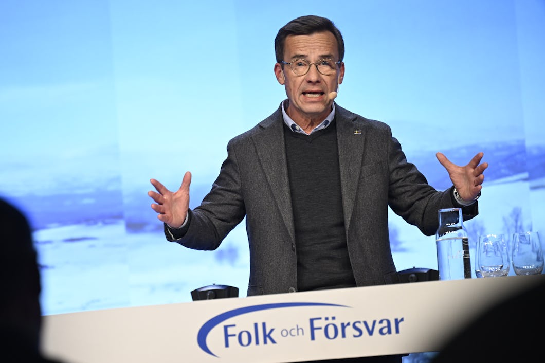 En man talar vid ett podium framför en skärm.