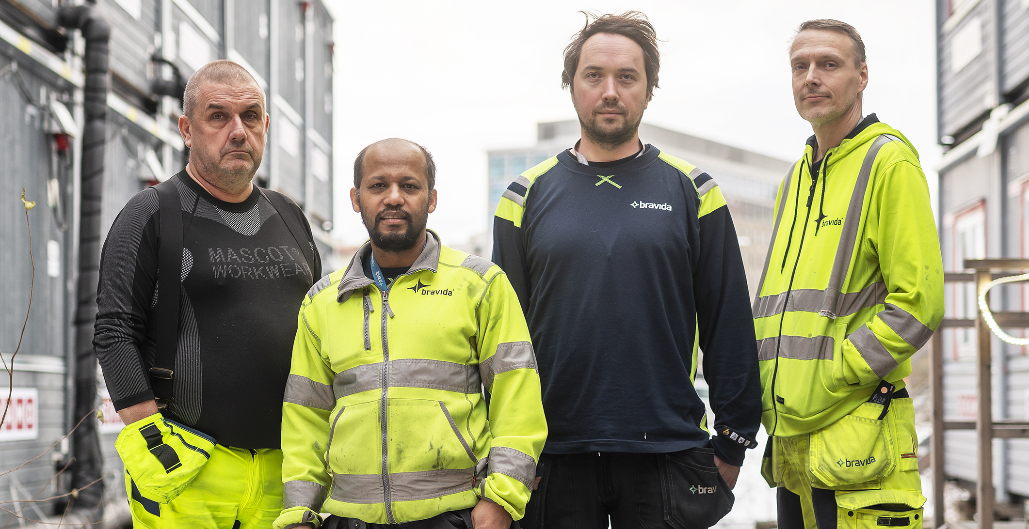 Fyra män i gula västar på ett bygge.