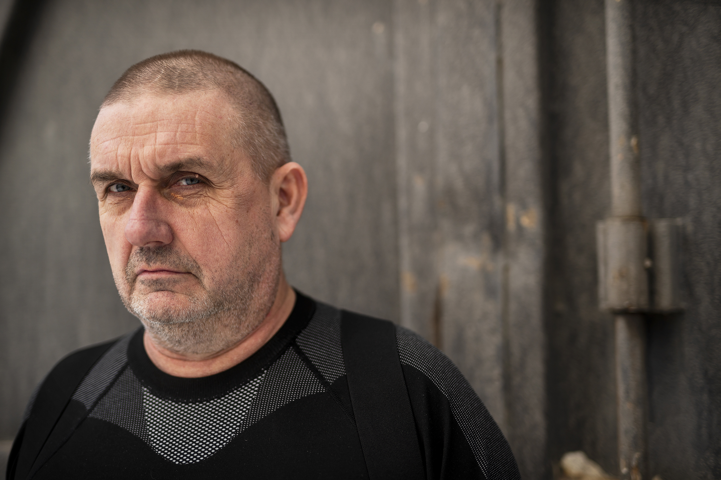 En man i svart skjorta stirrar in i kameran.