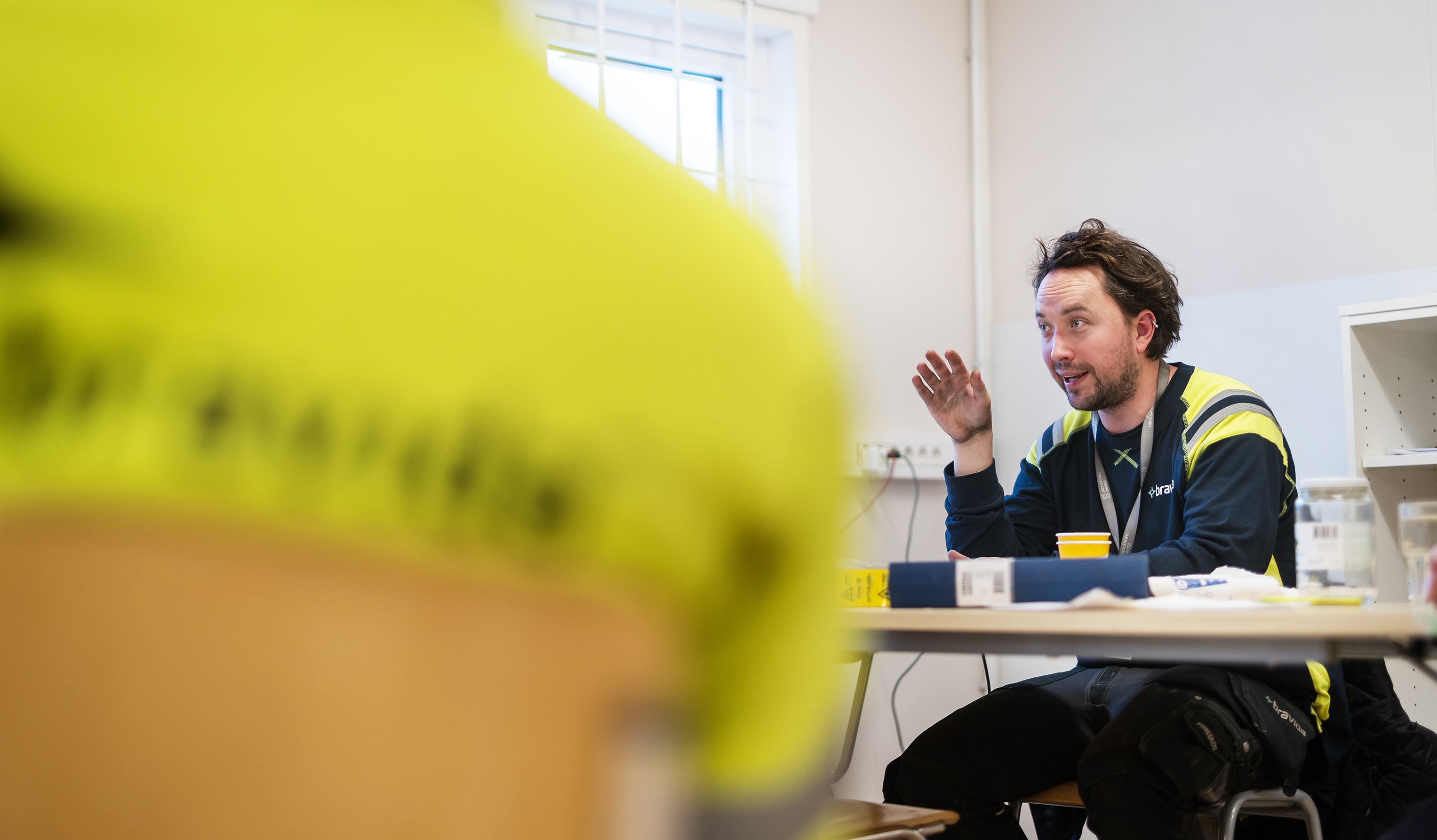 En man i en gul skjorta sitter vid ett bord.