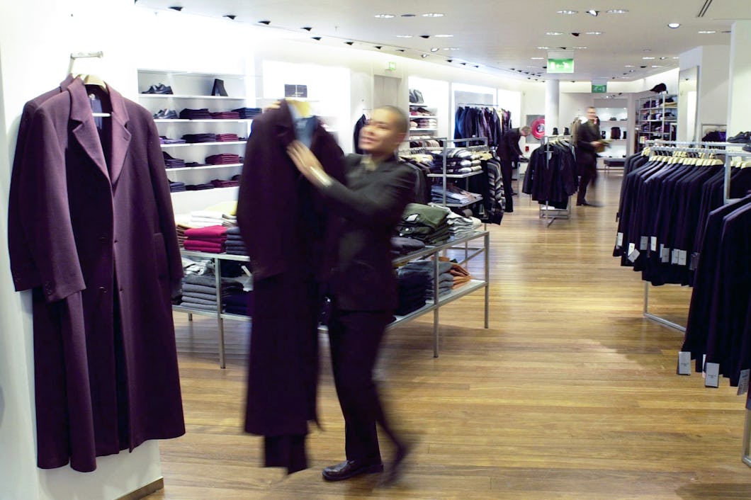 En person i en butik lägger ett vikt plagg på en hög.