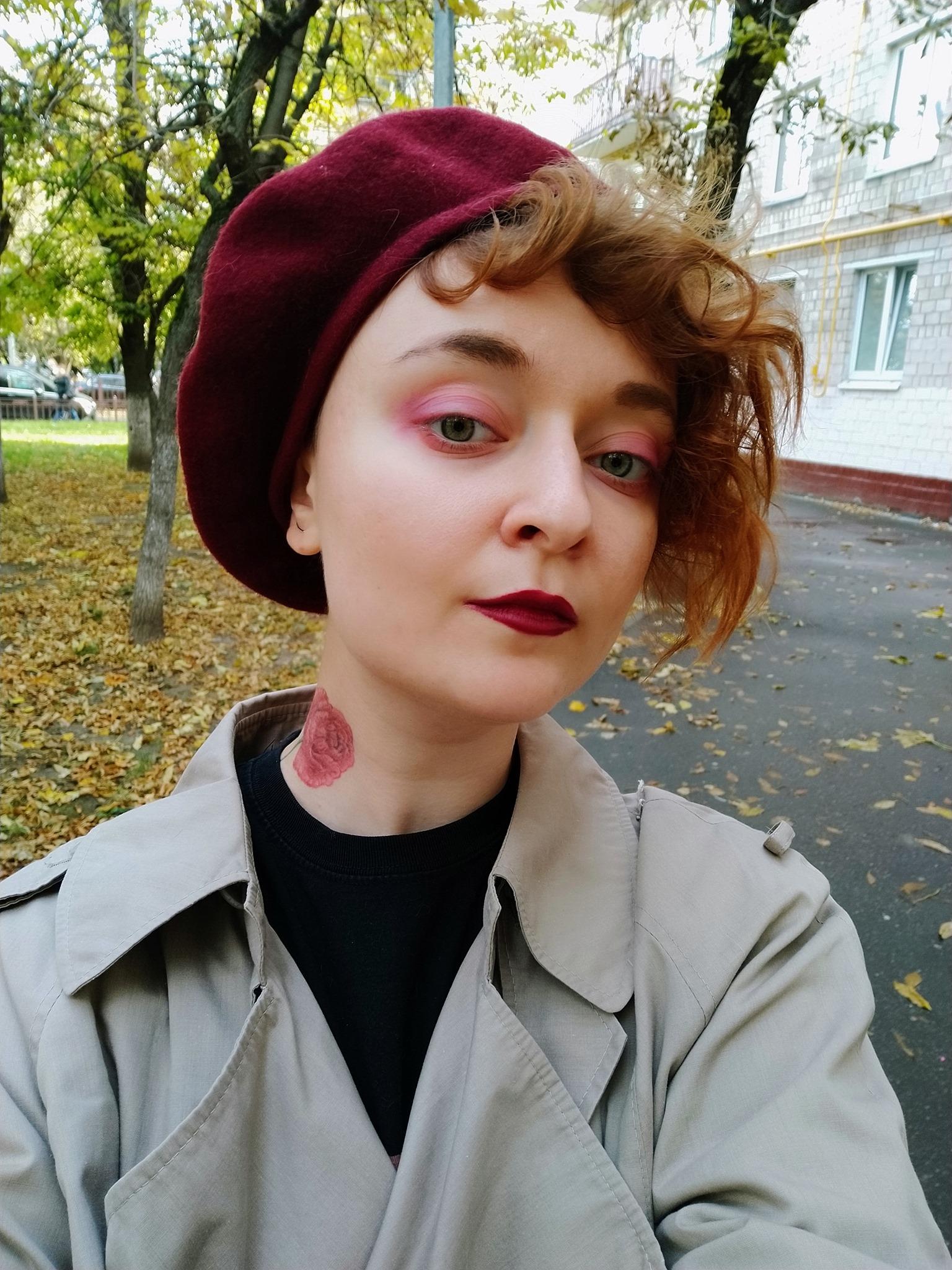 Daria Serenko klädd i en trenchcoat och en vinröd basker.