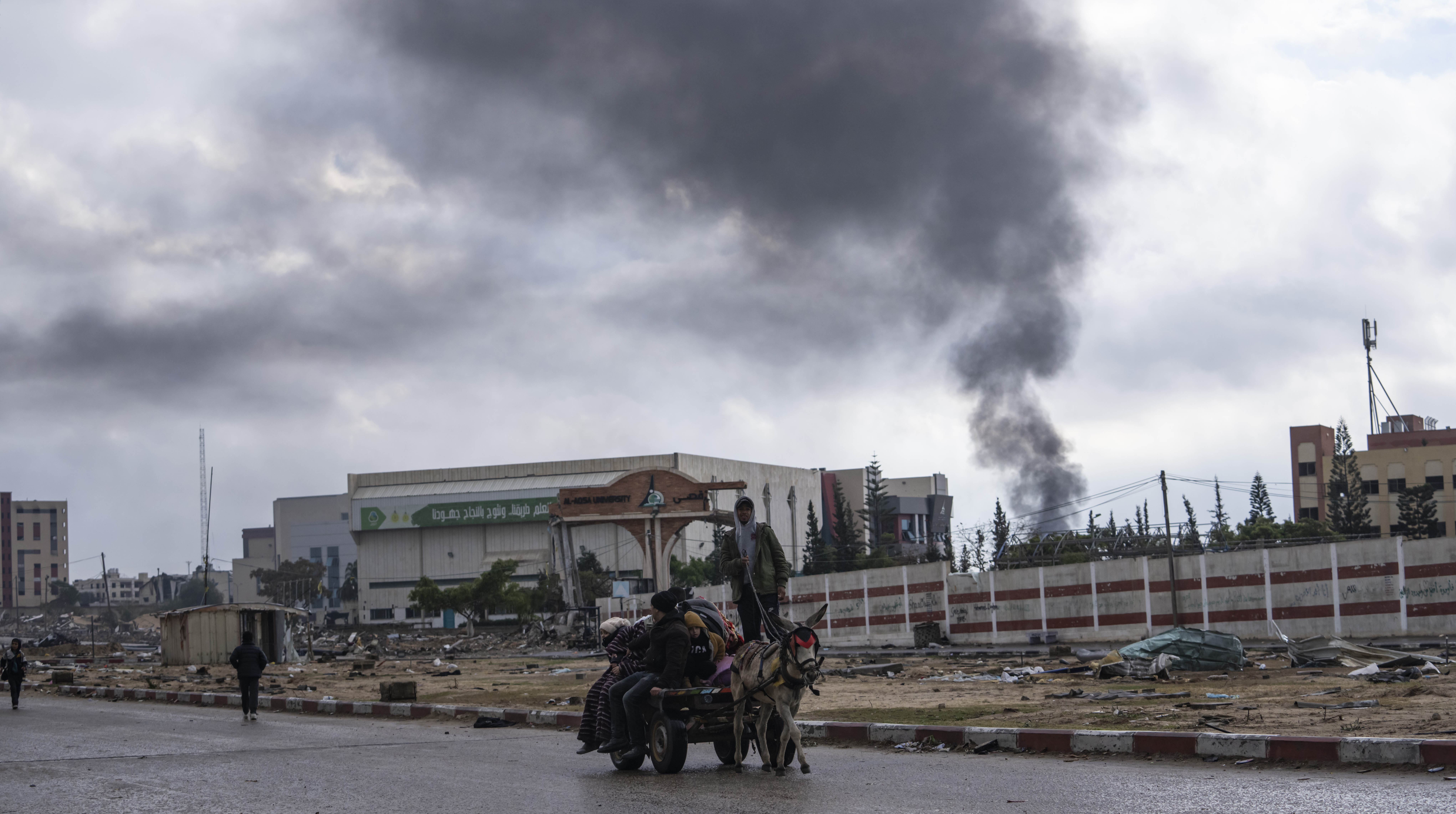 Personer på en gata med rök som väller bakom sig.