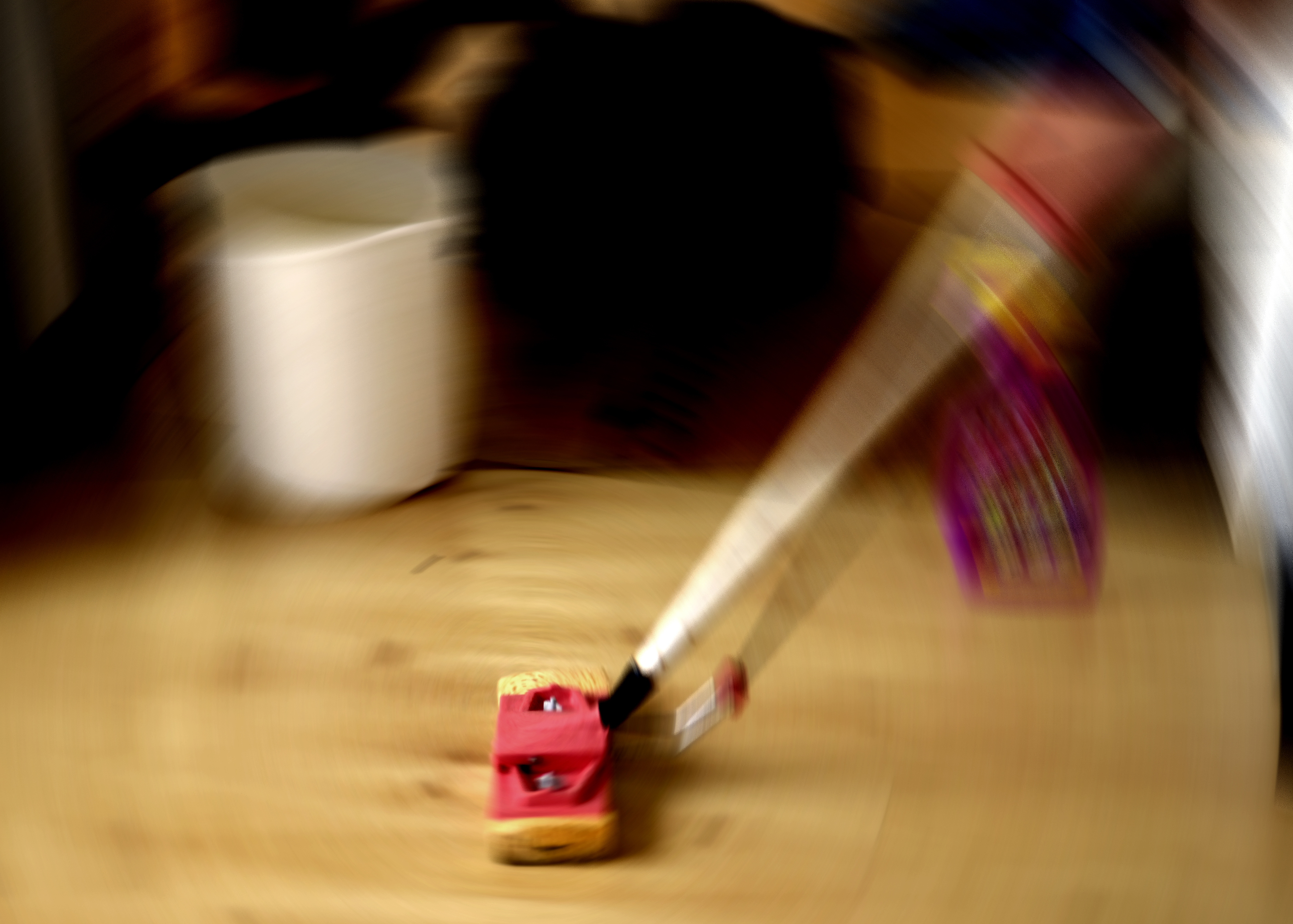 En person som använder en mopp på ett trägolv.